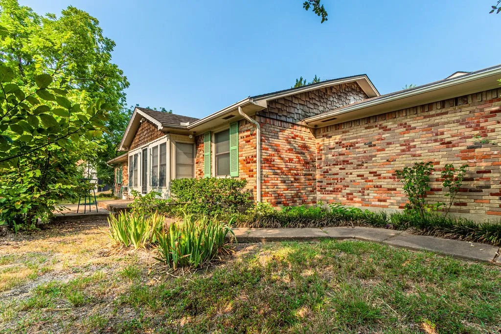 Brick exterior with a shingle-sided gable accent, prominent windows, and established landscaping
