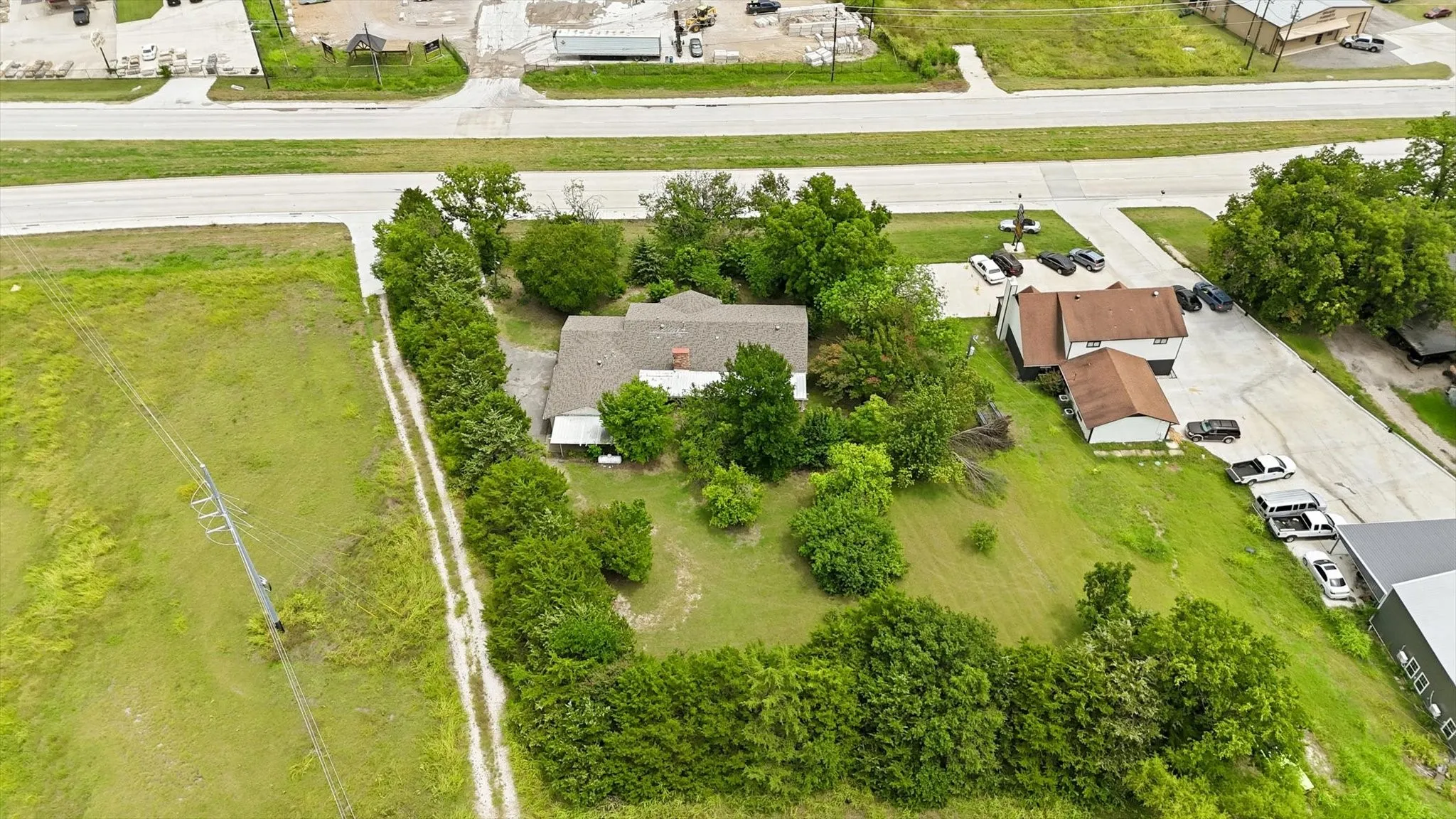 Expansive property featuring a central residence with a gabled roof and surrounding mature trees