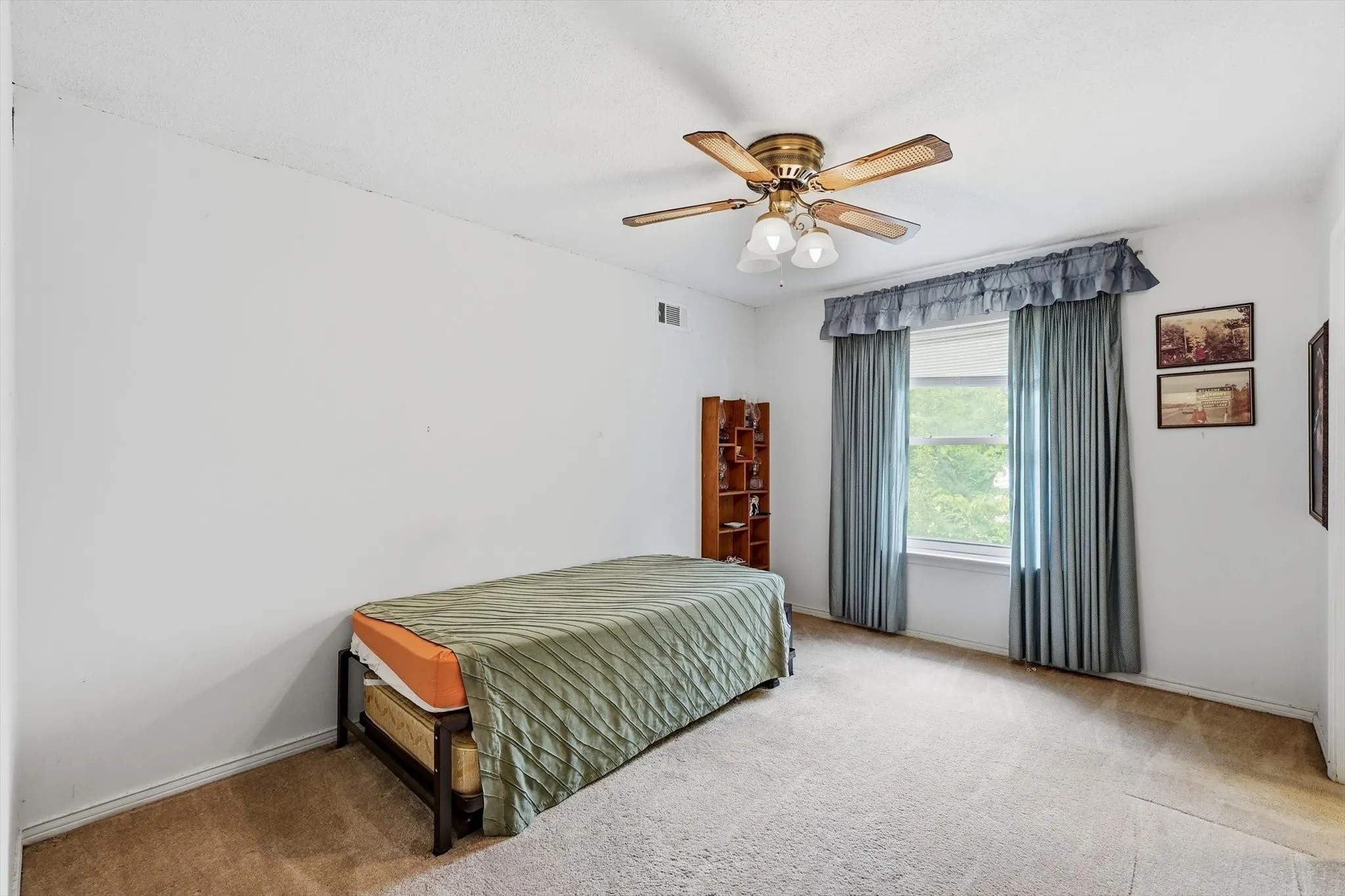 Carpeted room featuring a window with drapes, a ceiling fan with light fixture, and white walls