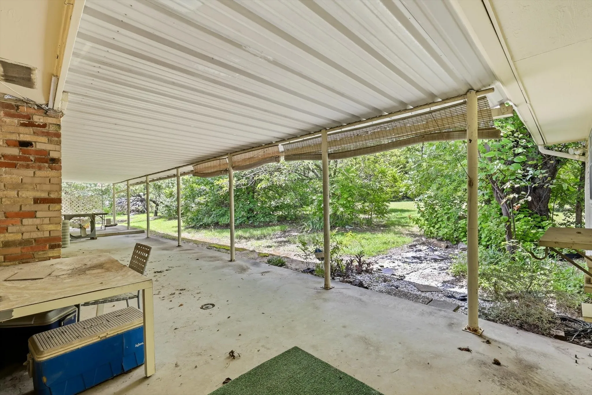 Covered patio area featuring a concrete slab, metal roofing, and brick exterior wall