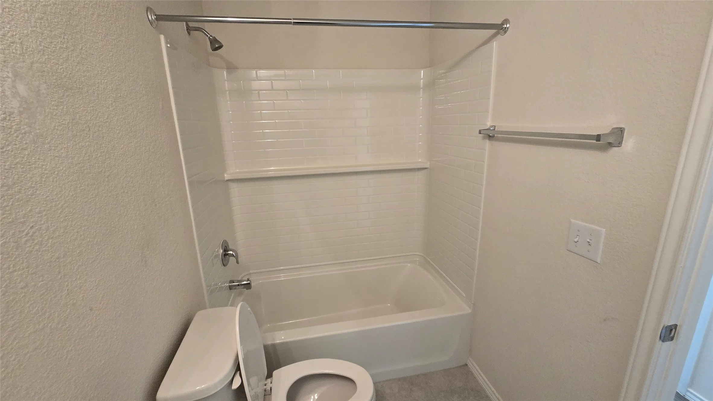 Full bathroom featuring a white porcelain toilet, a shower/tub combination with a subway tile surround, and brushed nickel fixtures