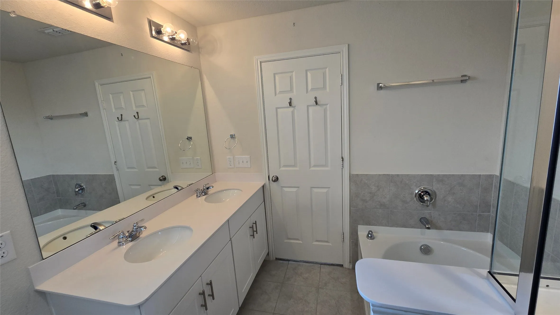 Bathroom featuring a double vanity with white cabinetry, light-toned countertops, and dual undermount sinks