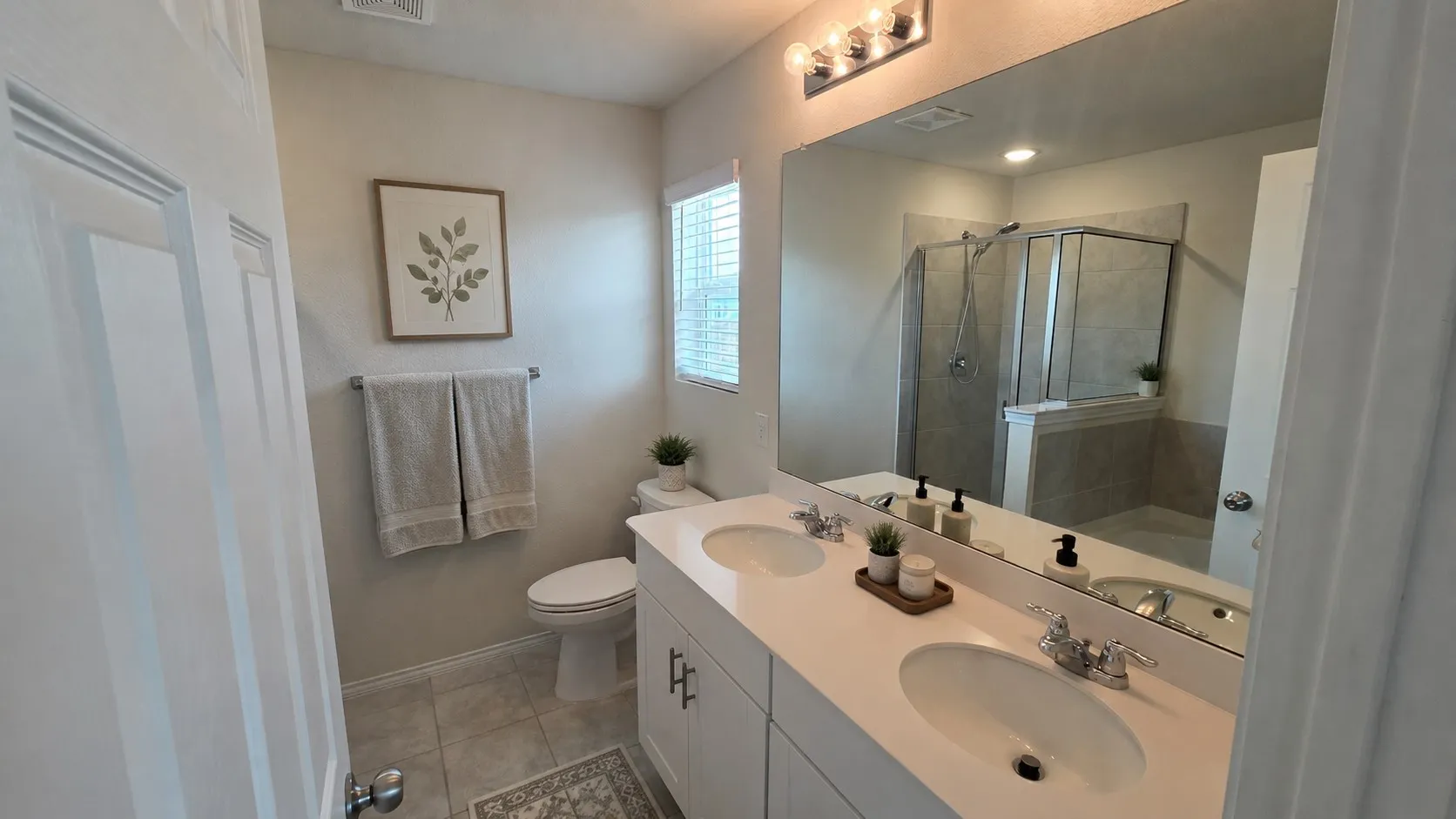 Virtual furnishings. Bathroom featuring a double vanity with undermount sinks, a large wall-mounted mirror, and a combination shower/tub with tile surround