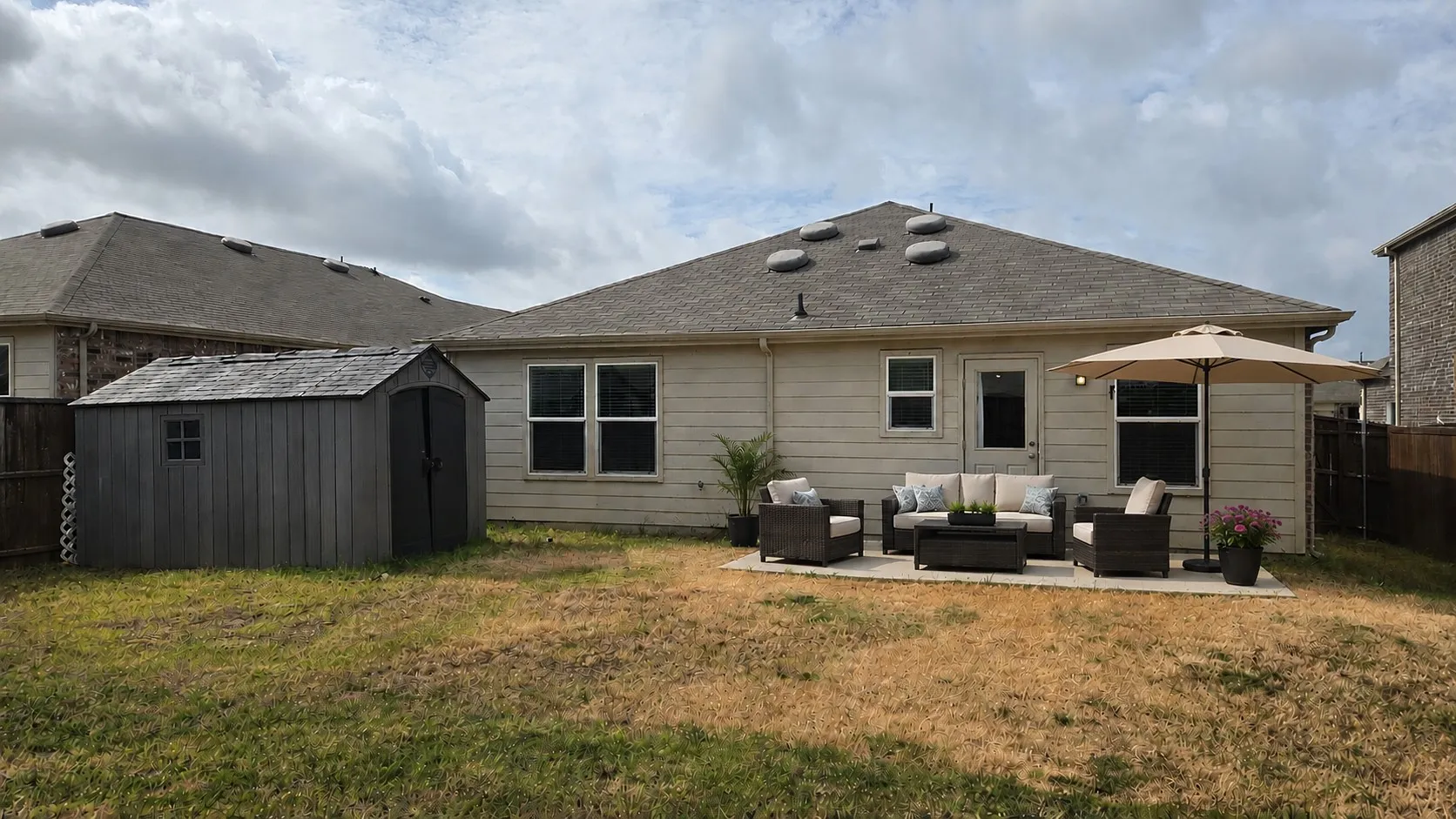 Virtual furnishings. Expansive backyard featuring a concrete patio, exterior lighting, and a storage shed