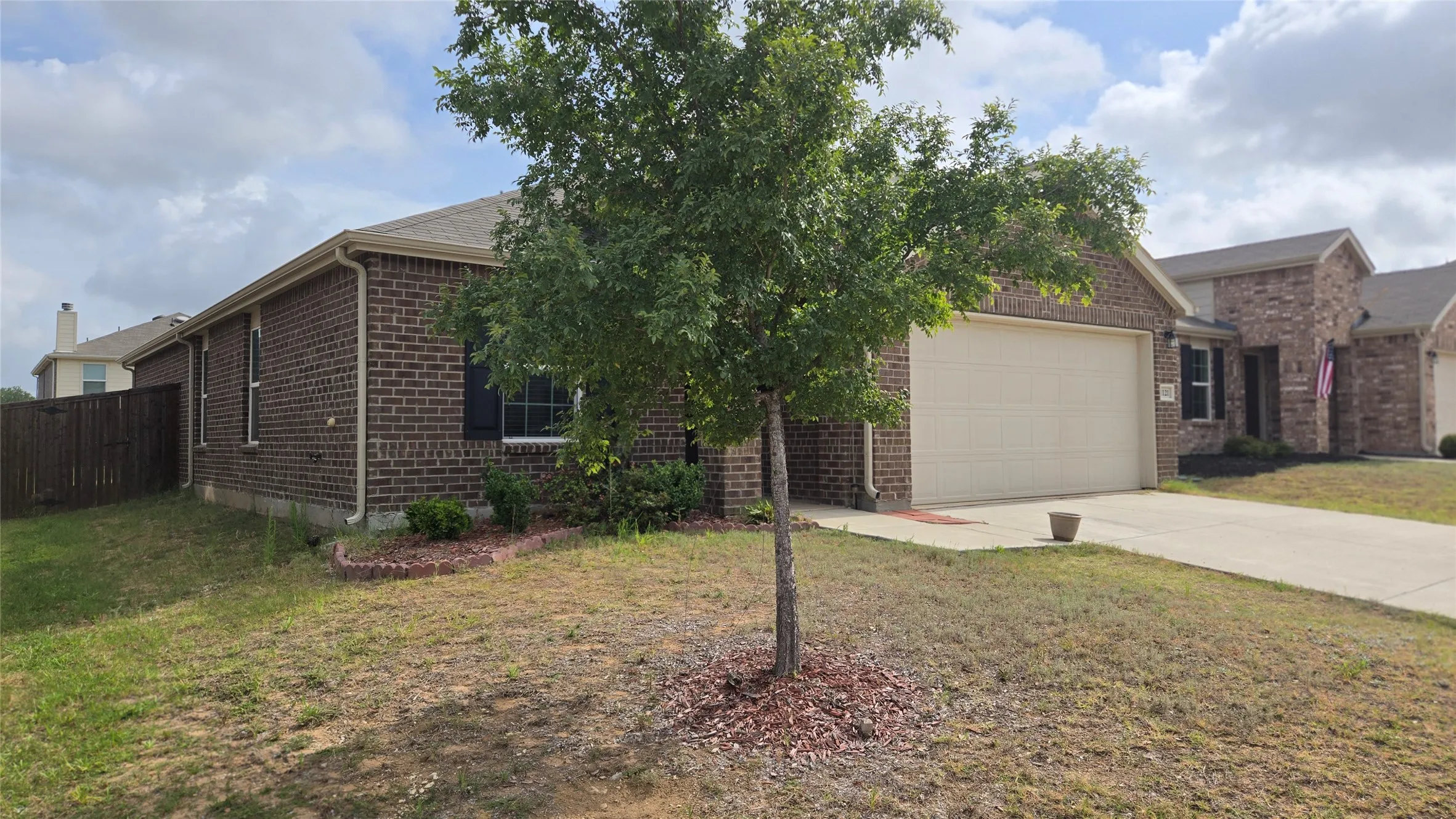 Brick exterior with dark shutters, an attached garage, and concrete driveway