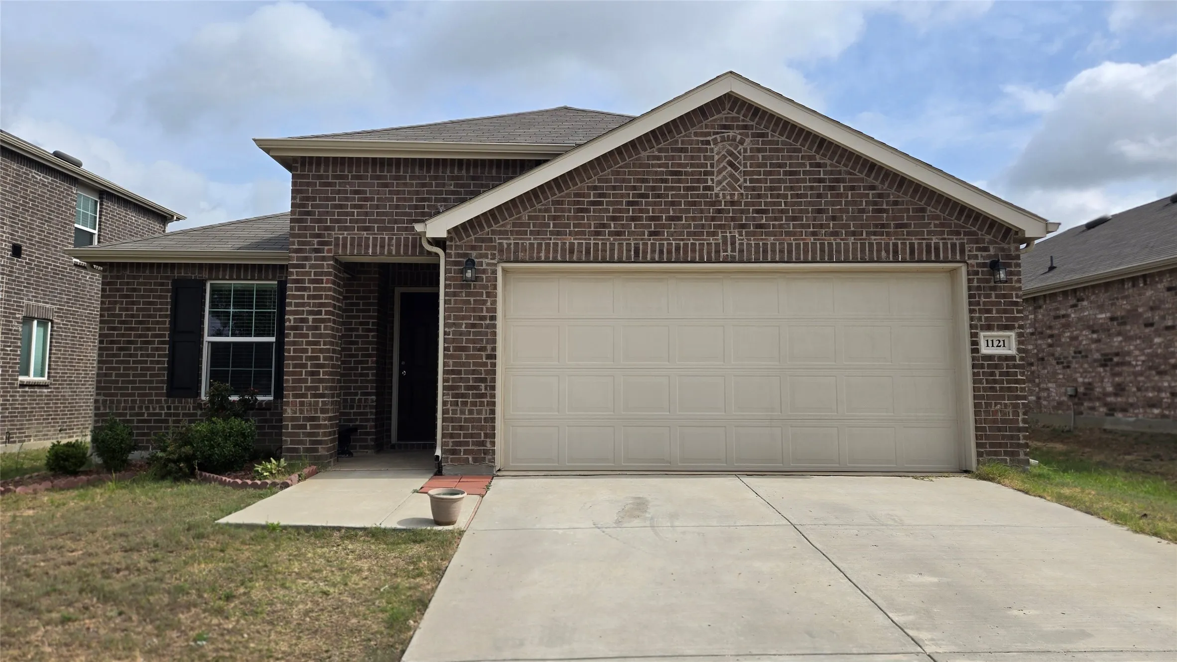 Brick facade home featuring an attached two-car garage with an overhead door