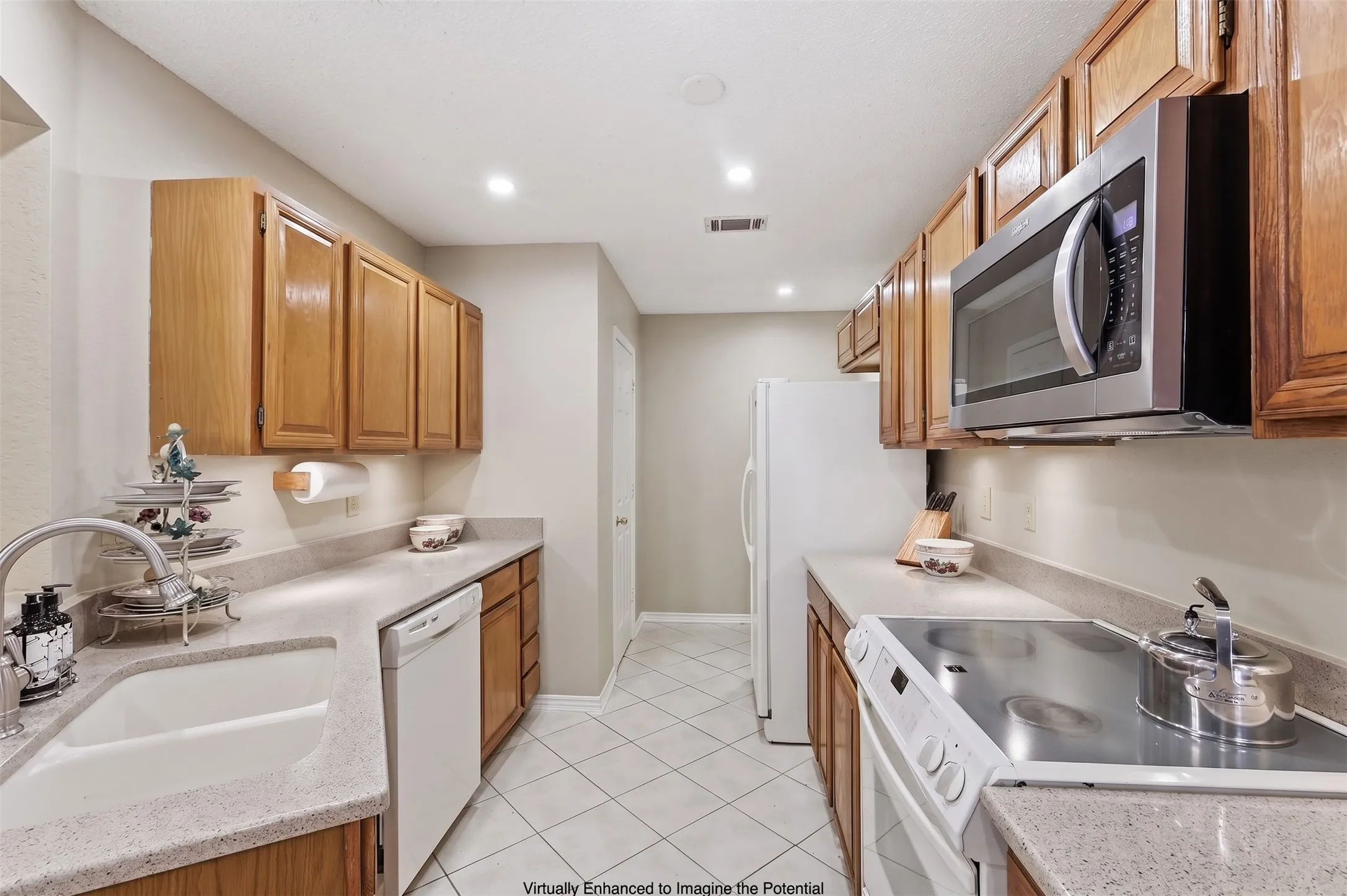 Kitchen featuring wood cabinetry, stone-finish countertops, stainless steel microwave, white electric range, and tile flooring