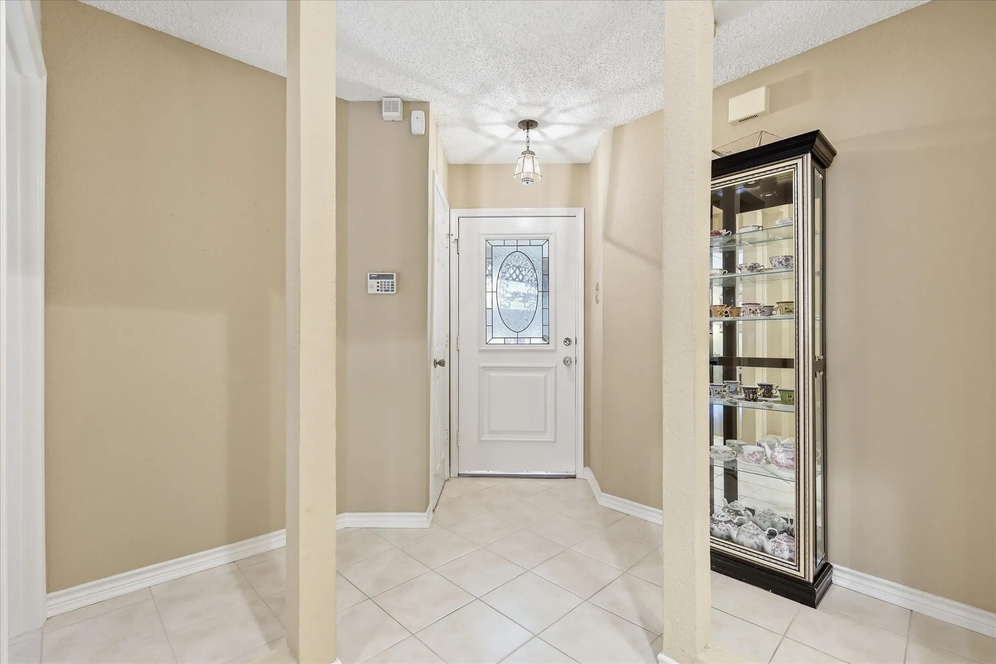 Entryway featuring a white door with decorative glass inserts, square tile flooring, and a ceiling-mounted light fixture