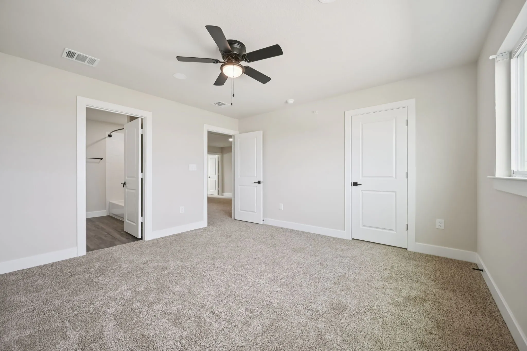 Carpeted room featuring a ceiling fan with integrated lighting, a window with white trim, and two-panel interior doors