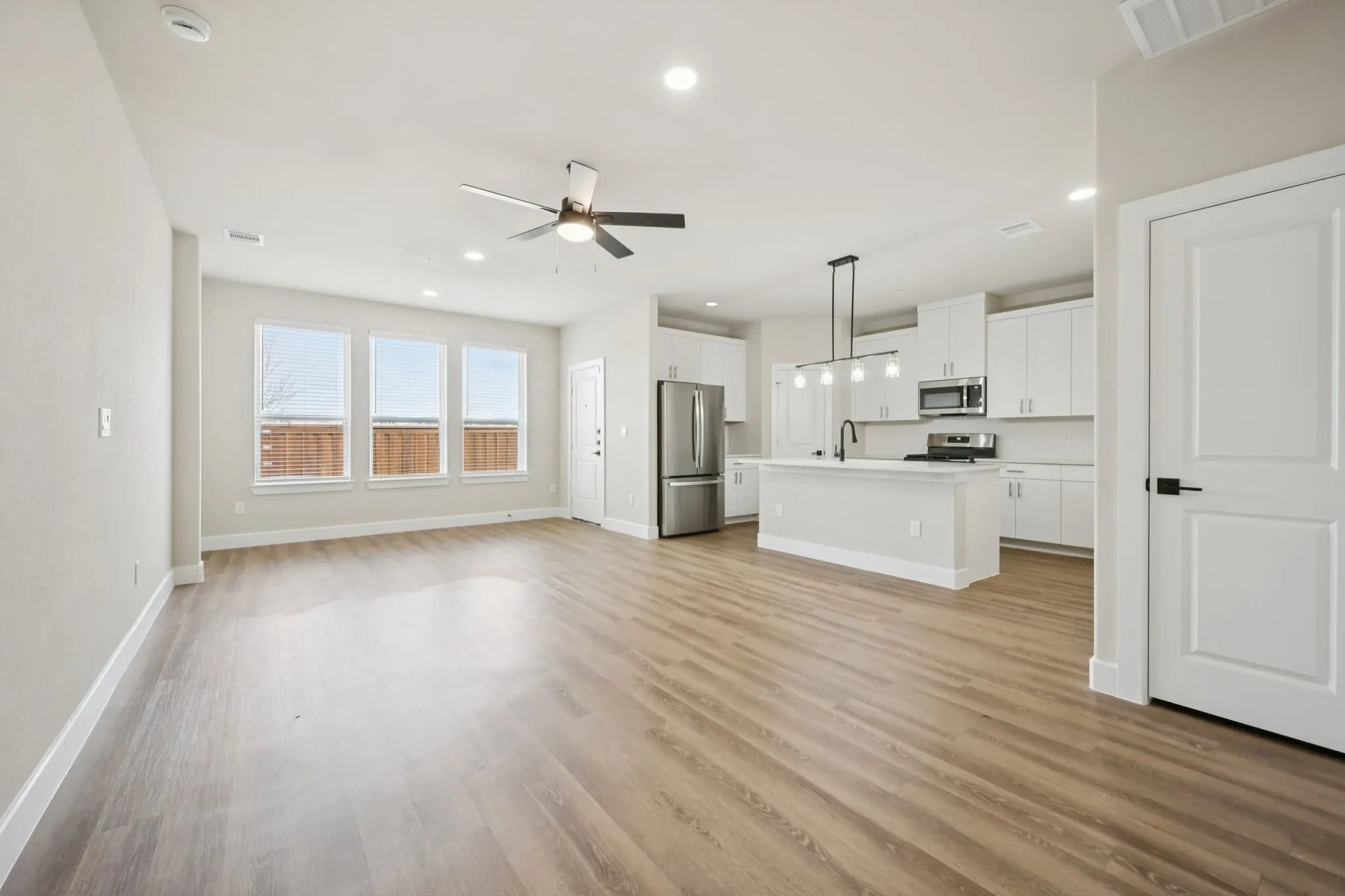 Open-concept living area featuring wood-finish flooring, recessed lighting, and a ceiling fan