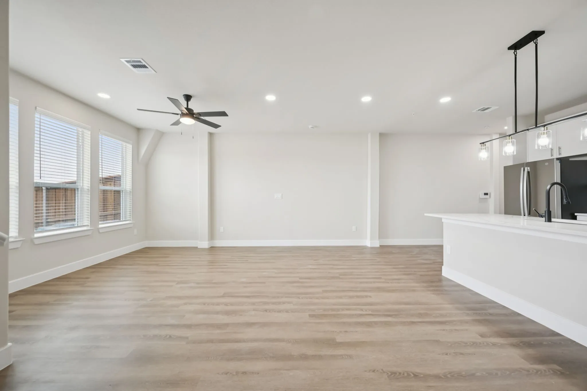 Expansive open-concept living area featuring wood-finish flooring, recessed lighting, and a contemporary ceiling fan