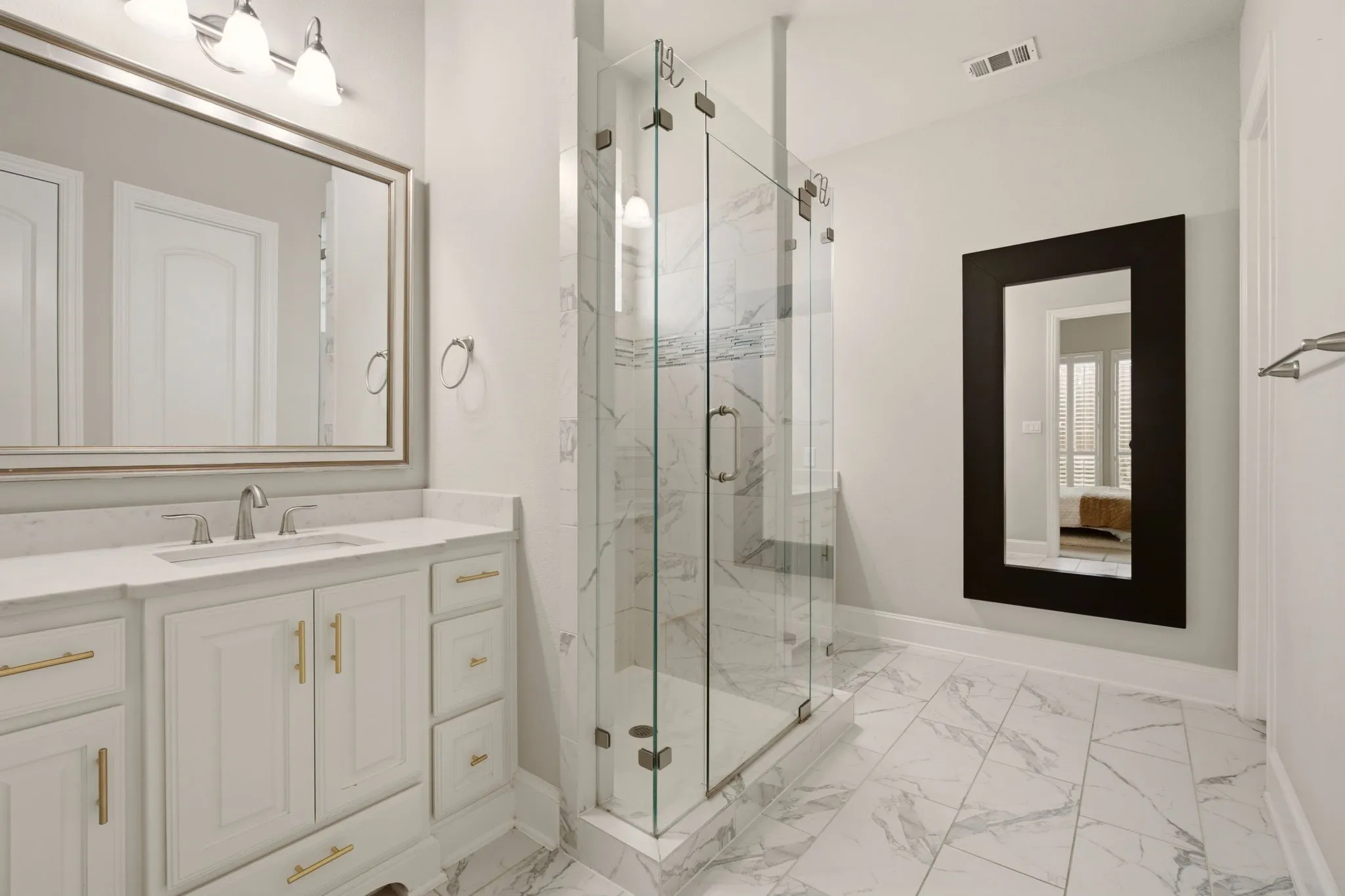 A meticulously maintained primary bathroom features a spacious frameless shower surrounded by two furniture-style vanities. Love the floor tile that extends into the shower. The adjoining primary closet adds valuable storage space, completing the well-designed primary suite.