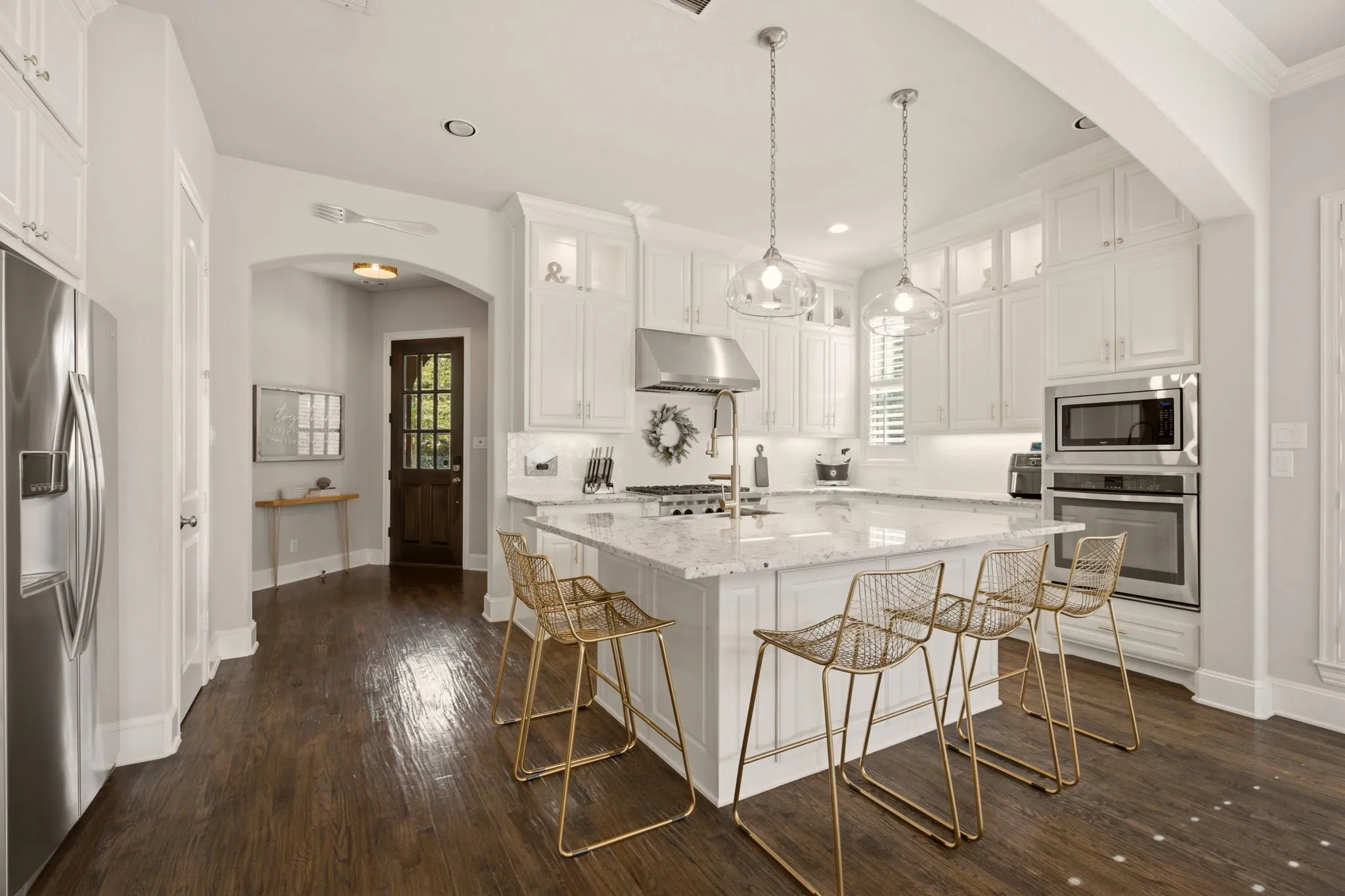 Designed with both beauty & function in mind, the chef's kitchen is a bright, timeless centerpiece of the home. An abundance of crisp white cabinetry—including elegant glass-front display cabinets—provides exceptional storage, while gleaming white granite countertops complimented by a diamond-pattern tile backsplash.