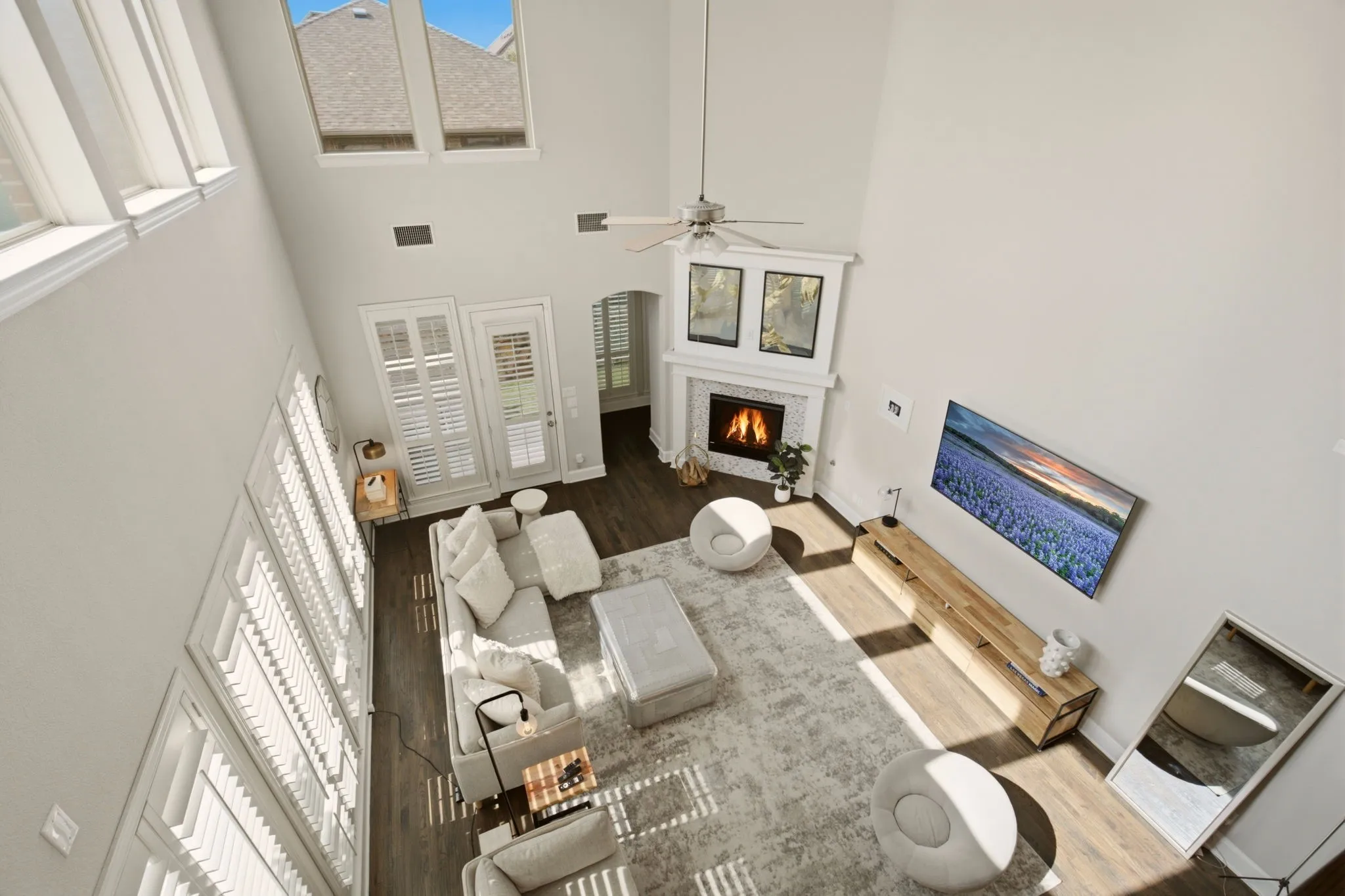 An aerial view shot looking down from the gameroom into the living room offers a dramatic, multi-level architectural perspective. This angle emphasizes the scale of a soaring, open-concept floorplan while seamlessly connecting the energetic vibe of the upper entertainment space to the cozy relaxation below.