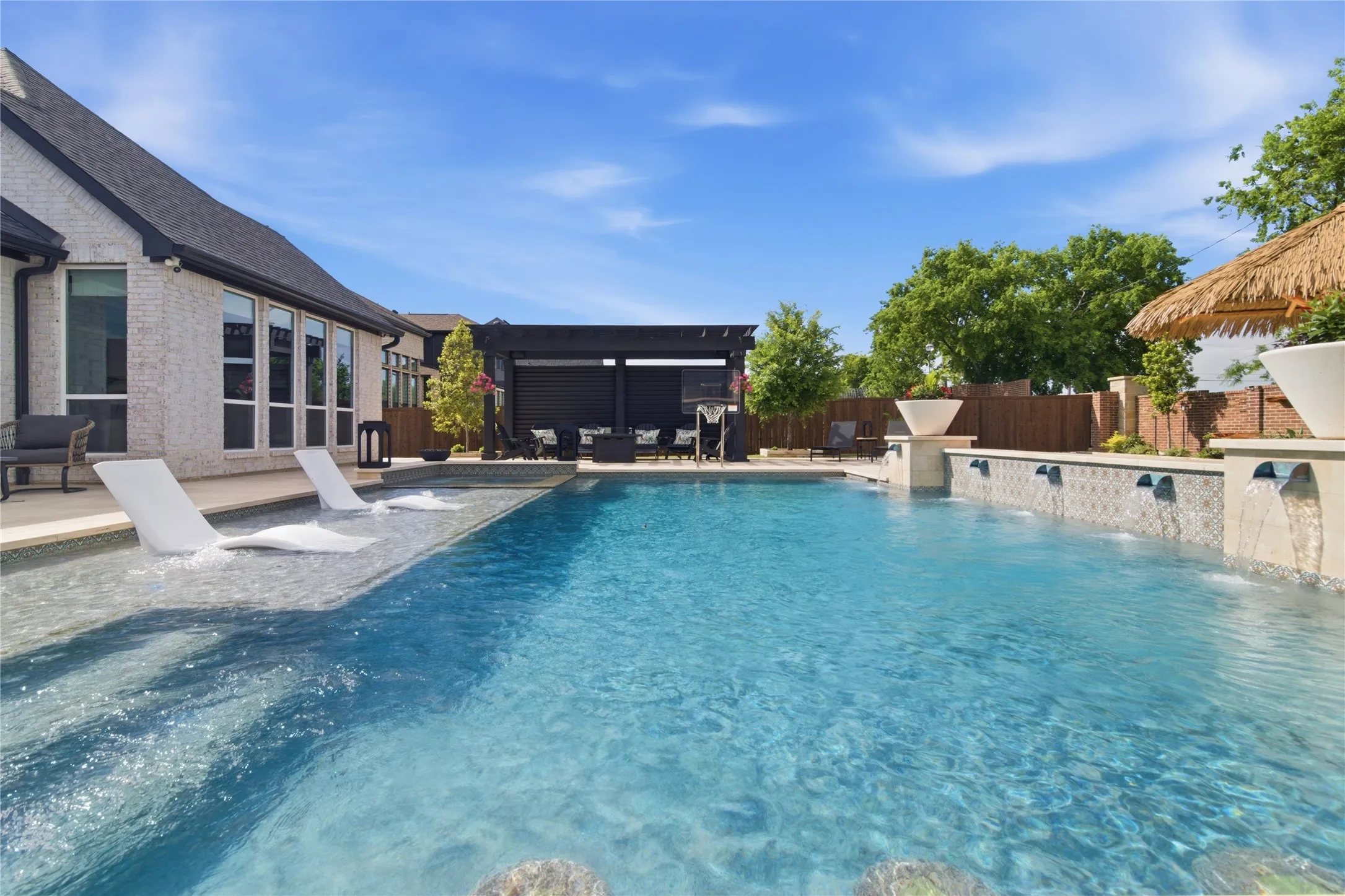 Inviting pool with beach entry, sundeck, swim up bar, water features.