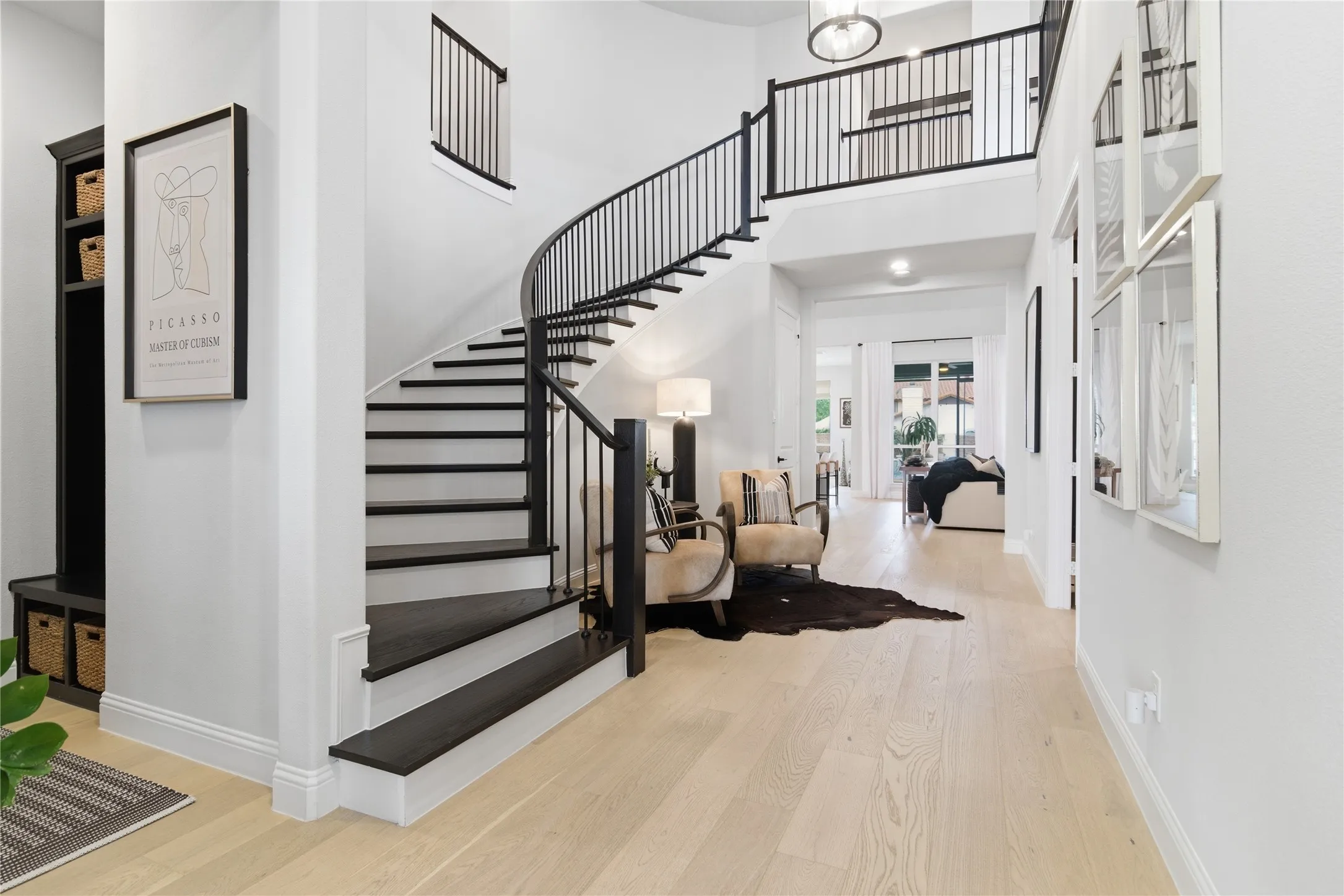 Extra wide entry. Curved, flowing staircase, sitting area at curve. Wood risers, wrought iron balusters with sleek flat handrail design.