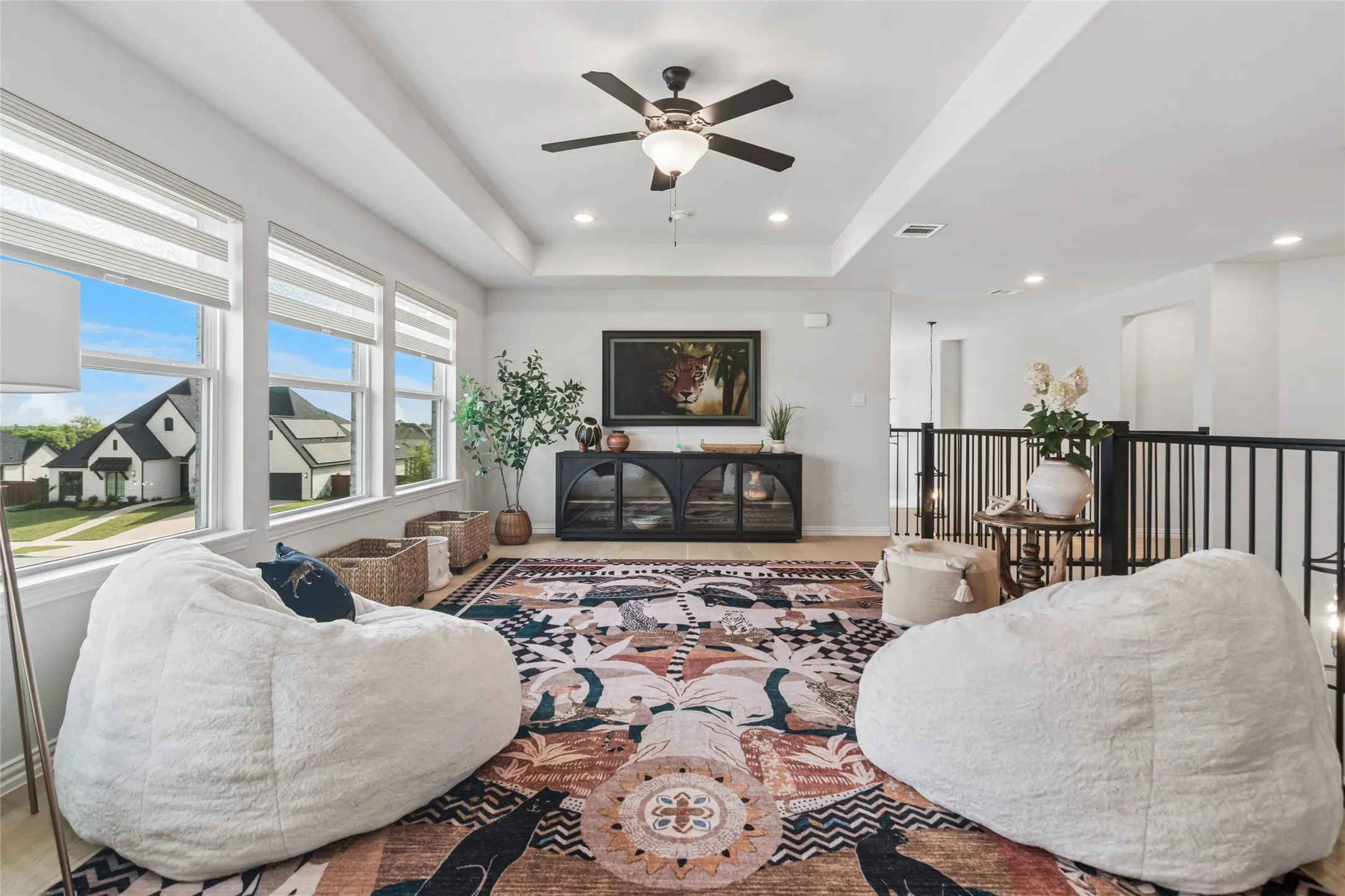 Second floor living area at the top of the stairs with tray ceiling, lots of natural light, hard wood flooring.
