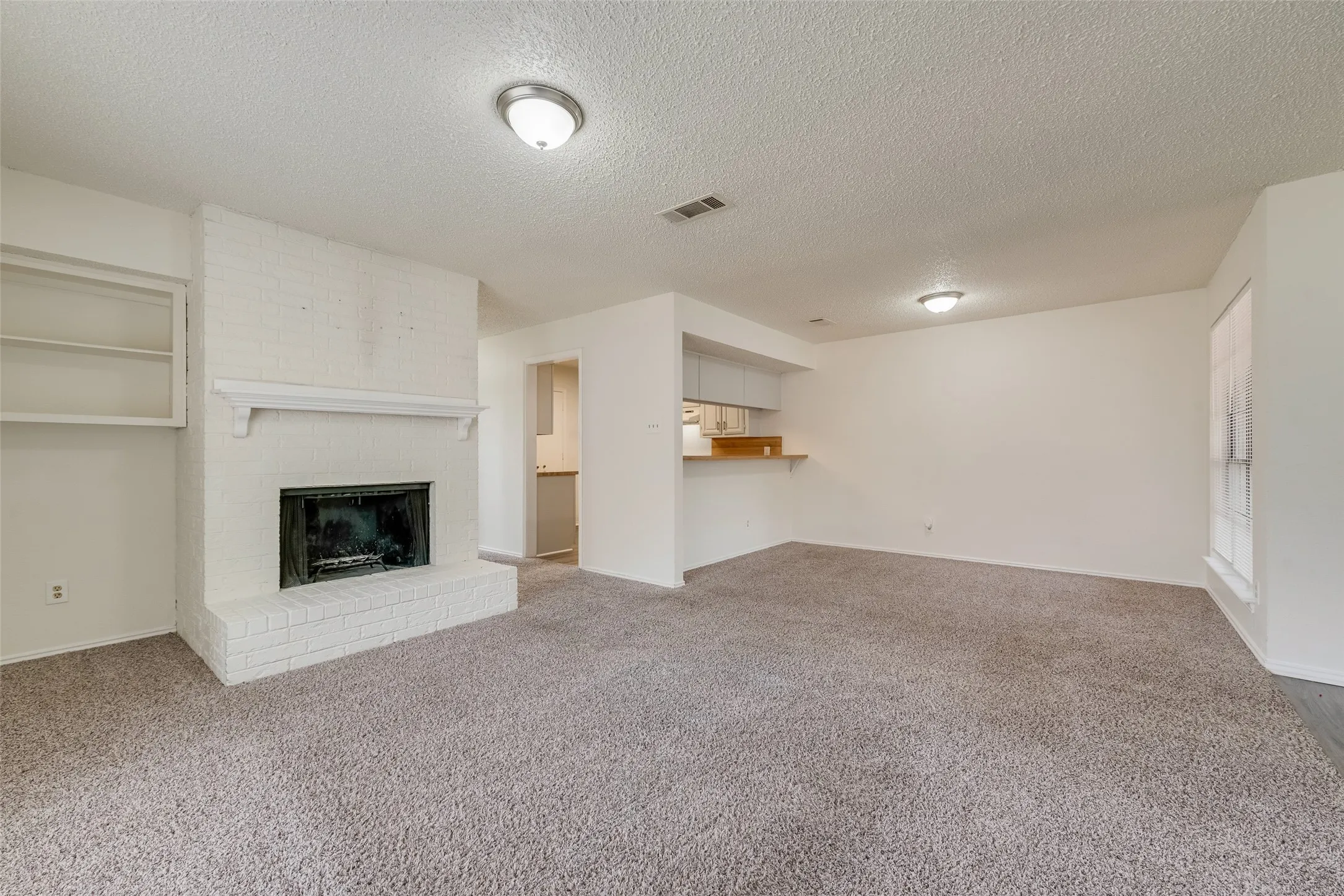 Living space featuring a painted brick fireplace with hearth, white mantel, and built-in shelving