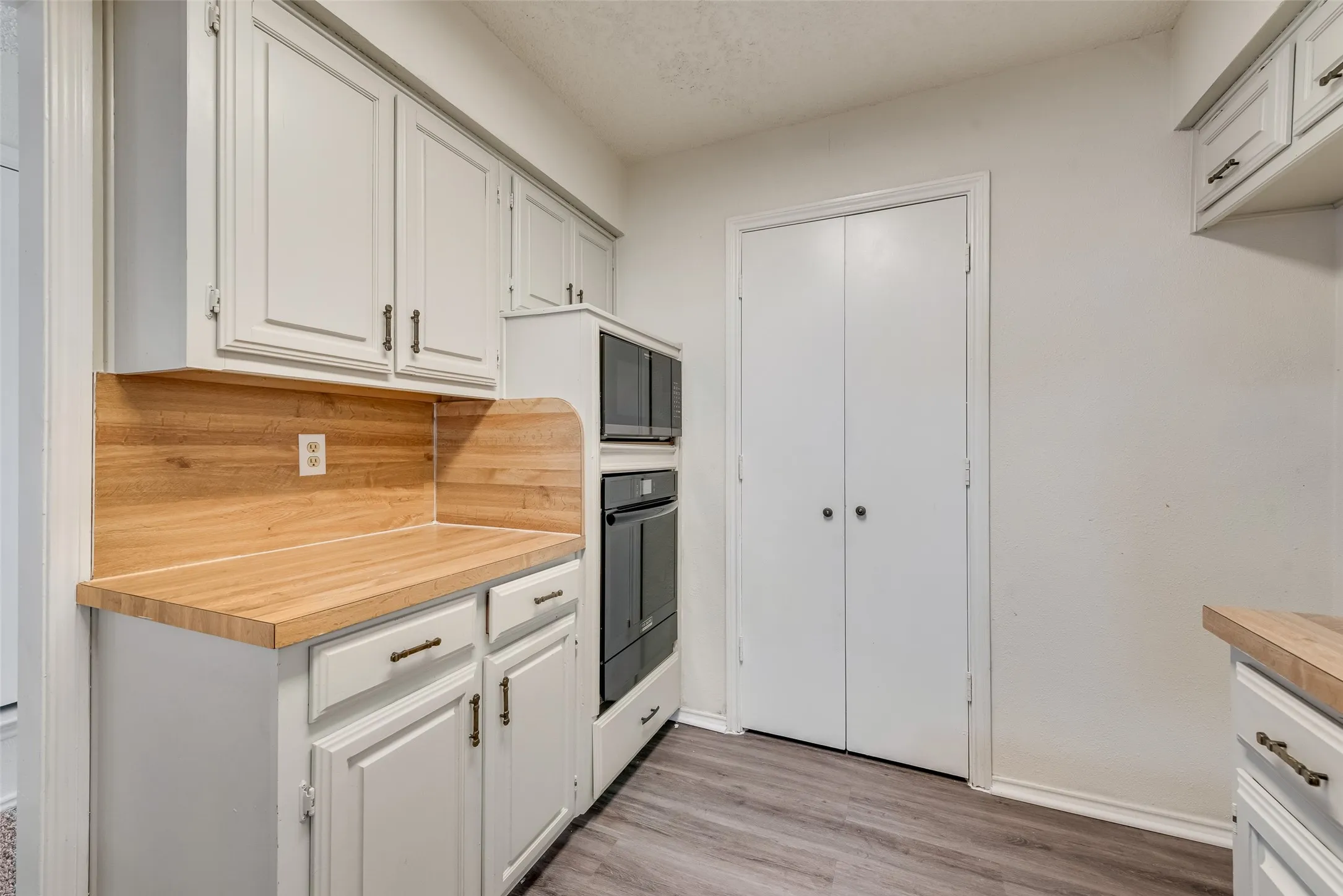 Kitchen featuring light-toned cabinetry, wood-finish countertops, and built-in appliances