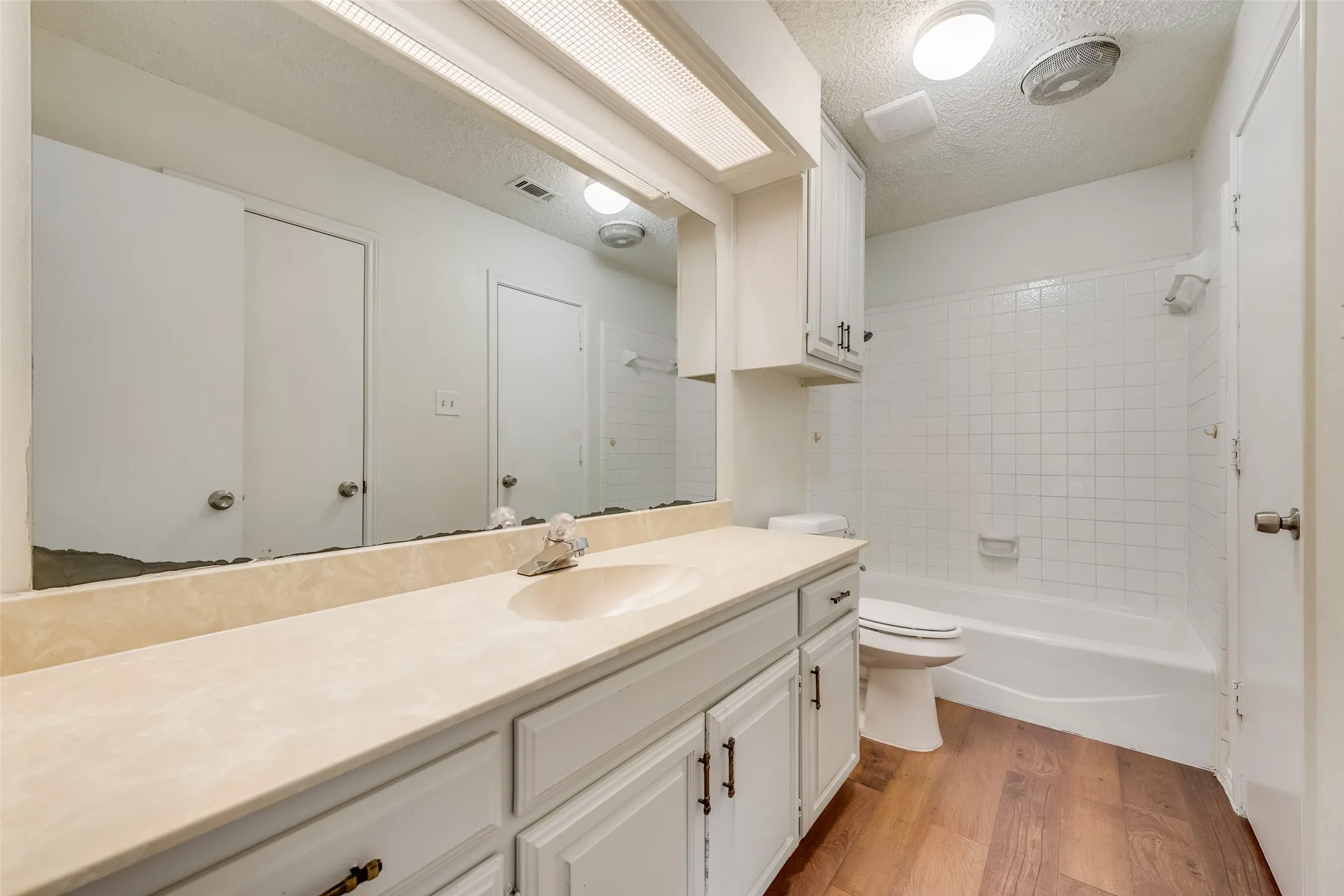 Bathroom featuring a long vanity with an integrated sink, cream-colored countertop, and ample under-sink storage