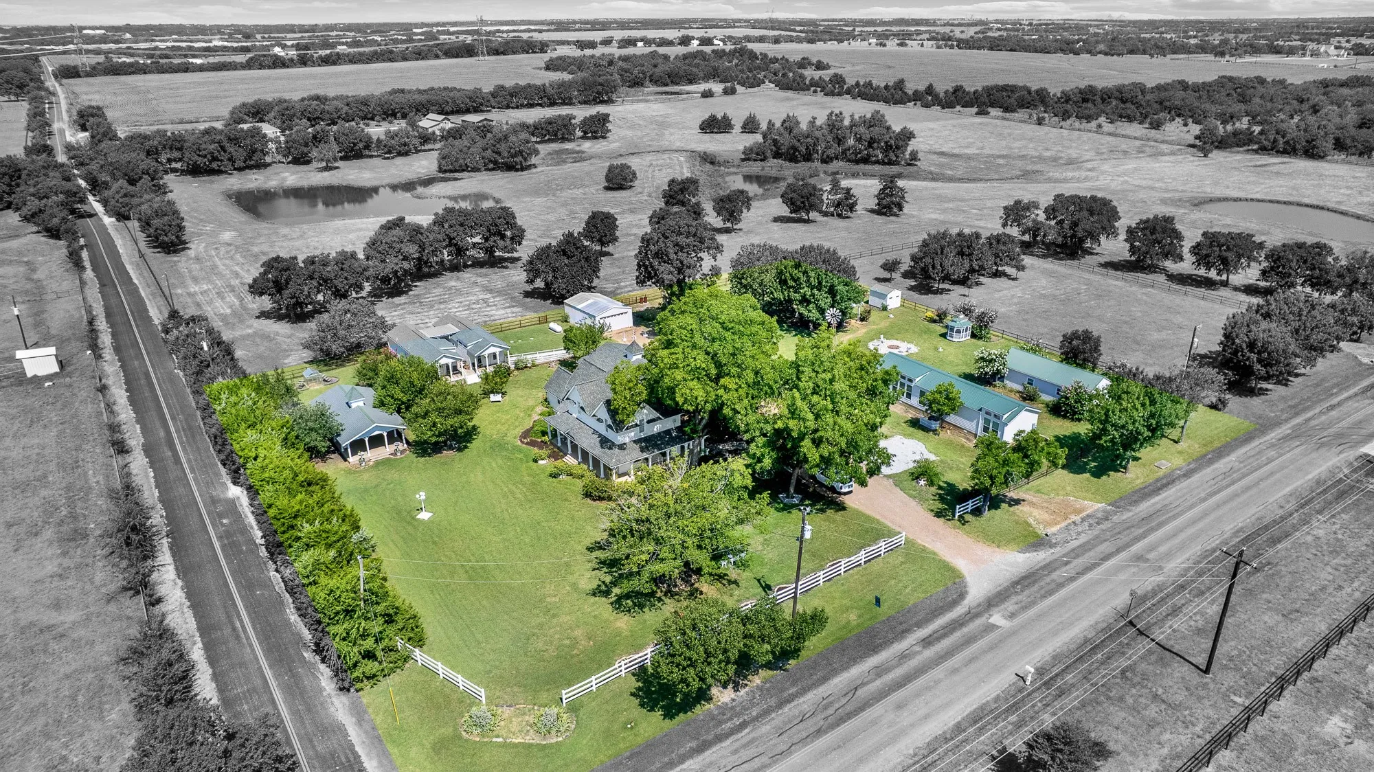 This aerial view showcases the thoughtful layout of the 2.44-acre estate, where the historic main residence, four income-producing rental cottages, and numerous outdoor amenities come together in one beautifully maintained setting. Mature trees, expansive lawns, a covered pavilion, gazebo, fire pit, and open green space create a private country retreat with exceptional versatility and investment potential.