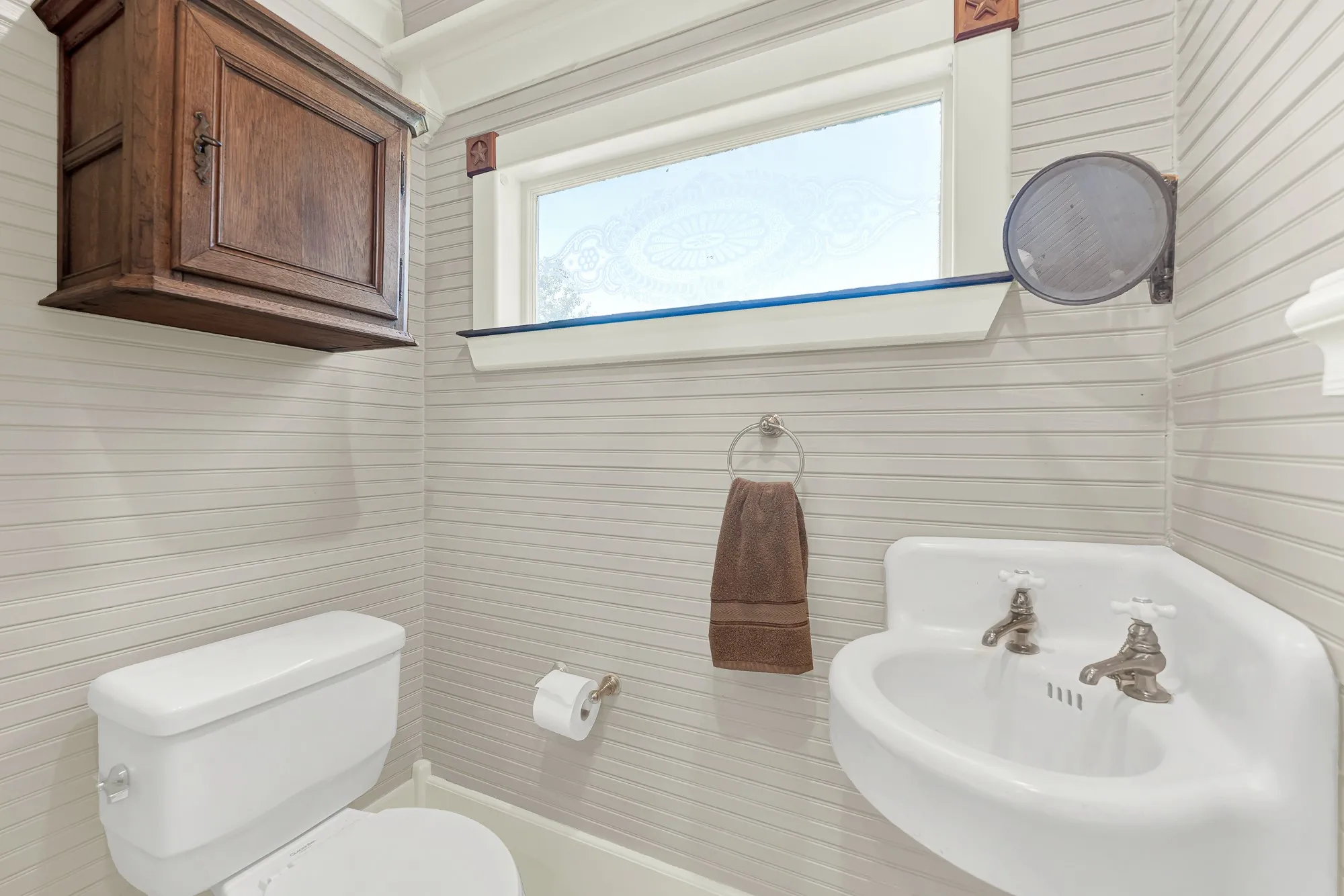 Conveniently located for guests, this charming powder bath complements the home's historic character with classic fixtures, vintage-inspired details, and abundant natural light, offering both style and functionality.