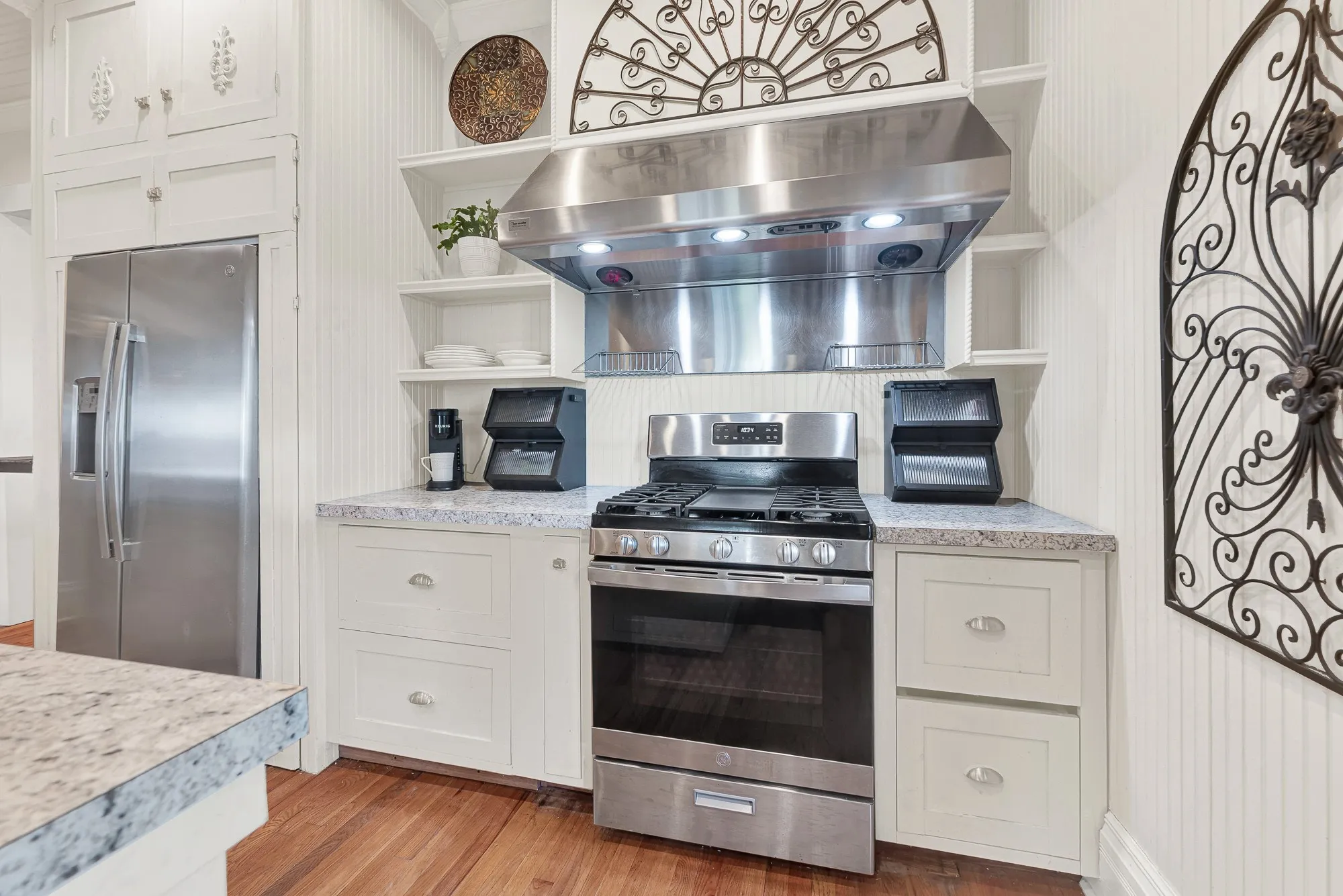 The custom vent hood and floor-to-ceiling cabinetry highlight the soaring ceilings and handcrafted details that give the kitchen its distinctive personality. Home-cooked meals feel right at home in a space that blends historic charm with everyday functionality.