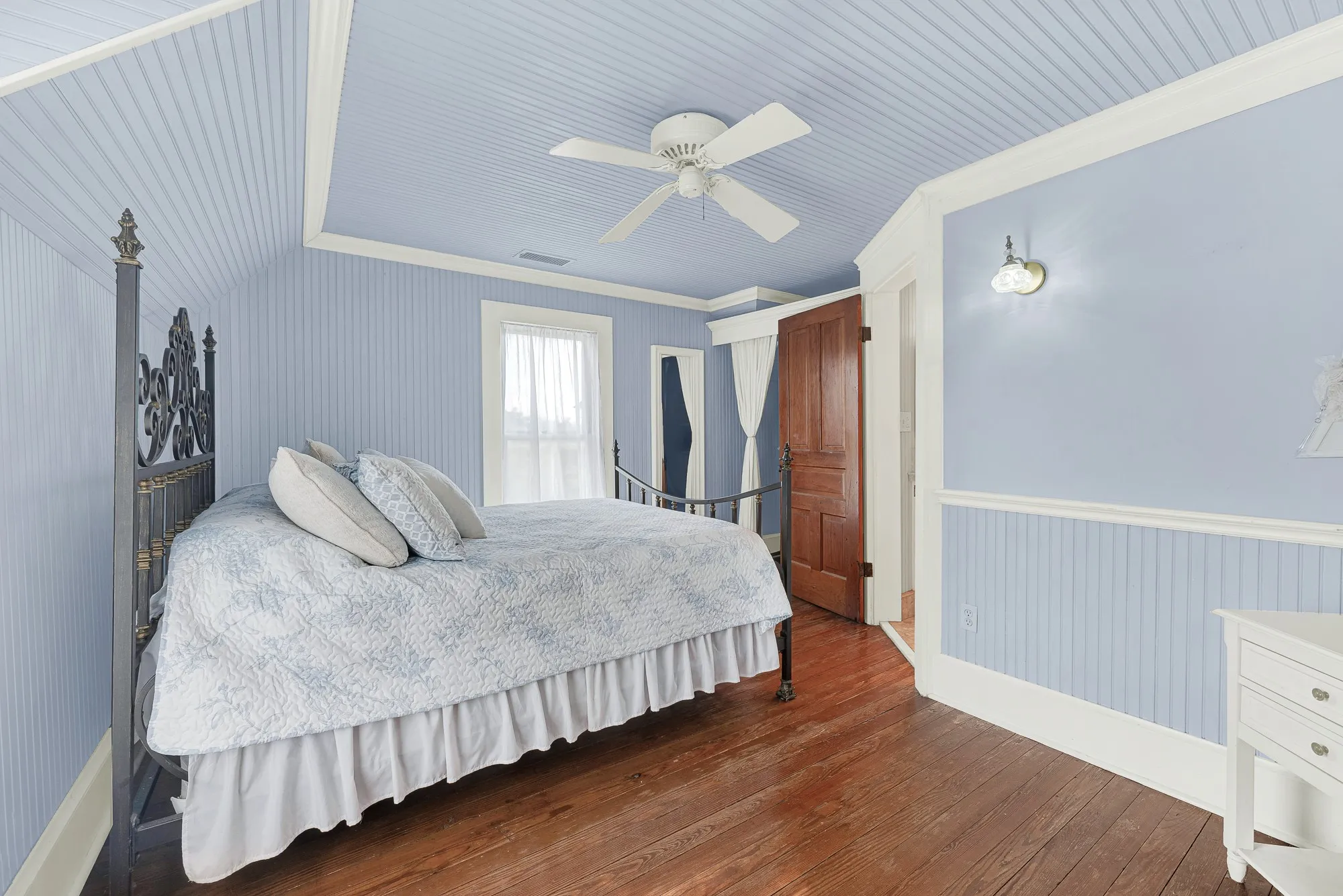 Soft beadboard walls and ceilings, paired with restored original hardwood floors, create a bright, welcoming bedroom that feels both timeless and comfortable. Guests or family can settle in, open the windows, and enjoy the peaceful rhythm of country living.