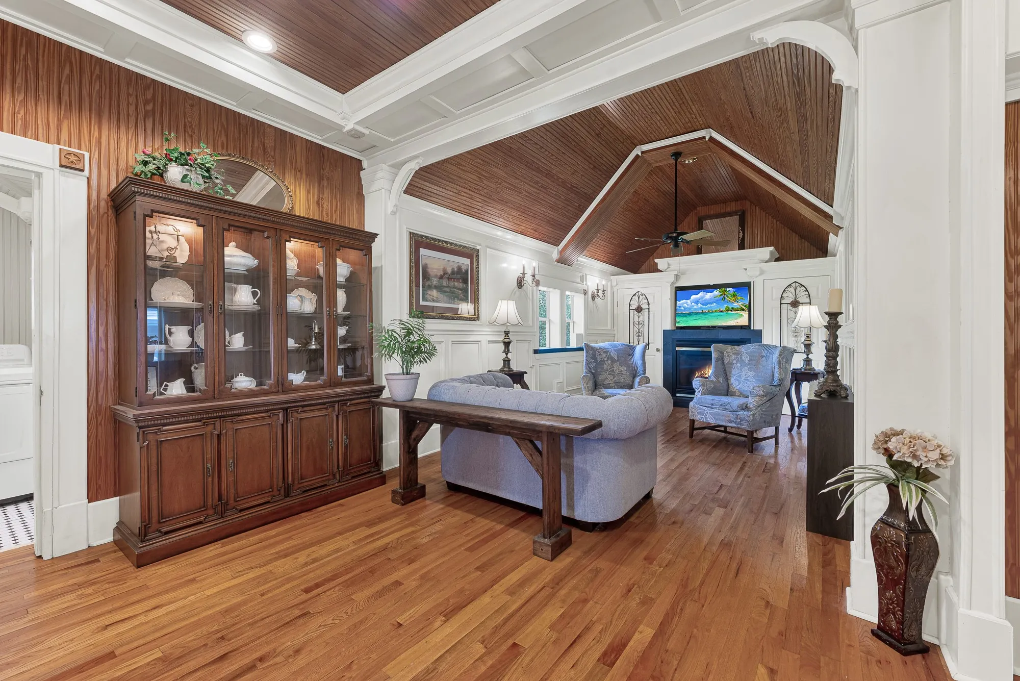 Rich wood ceilings and graceful architectural arches create a warm gathering space that feels both expansive and inviting. This is the room where movie nights, holiday conversations, and quiet evenings naturally become part of everyday life.