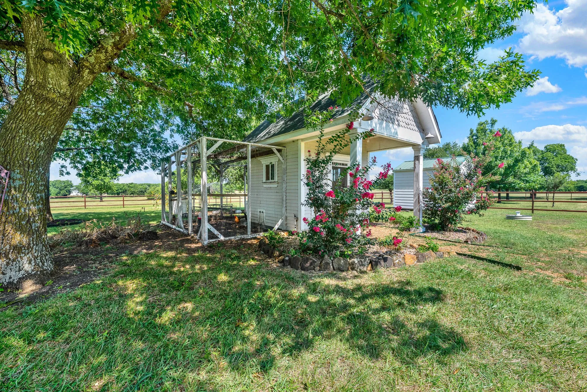 Tucked beneath mature shade trees, the charming chicken coop adds to the property's authentic country lifestyle. Surrounded by established landscaping and open pasture views, this area offers space for hobby farming, fresh eggs, or gardening, blending practicality with the peaceful rural character that defines the property.