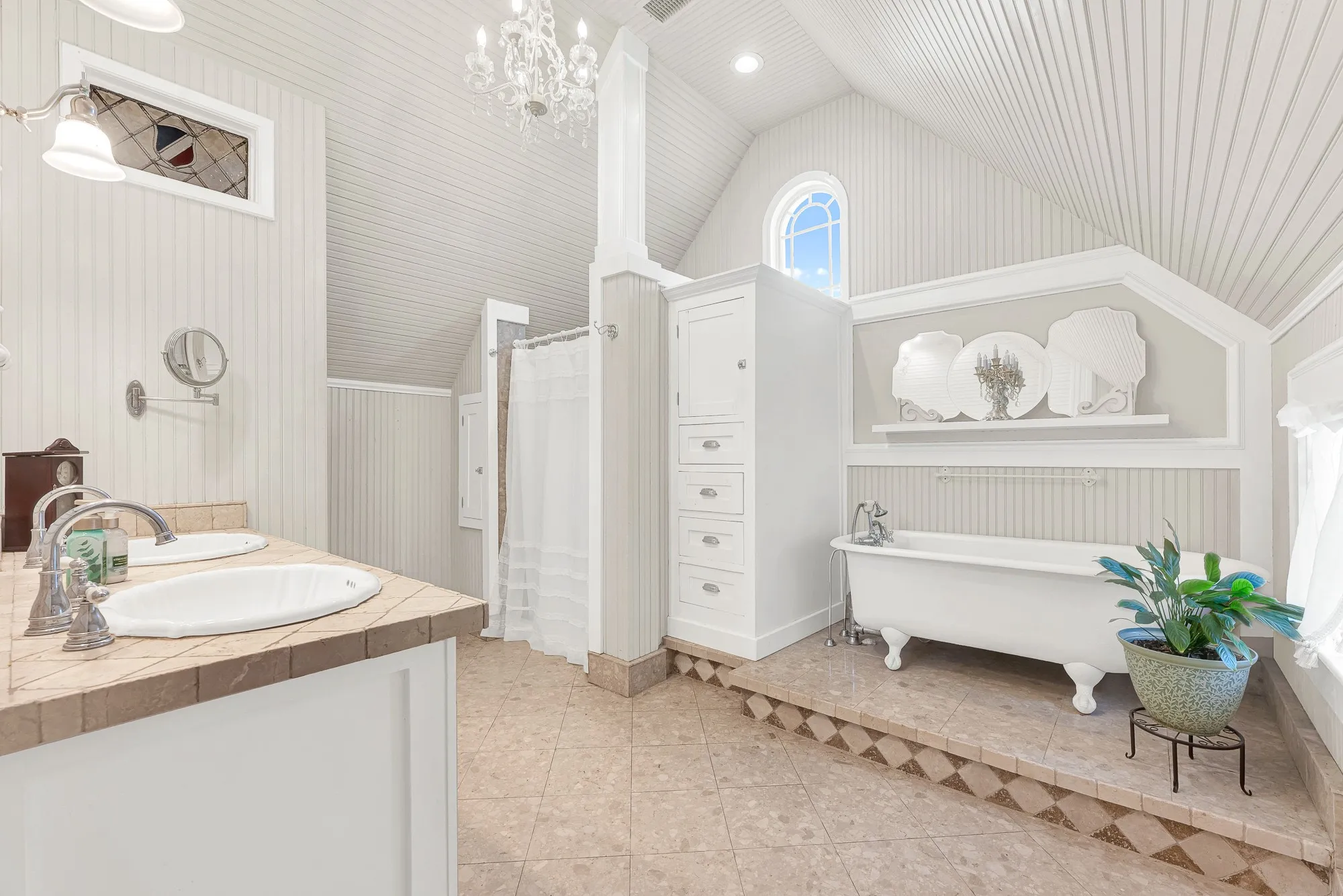 A clawfoot soaking tub, soaring beadboard ceiling, and arched window fill the bath with timeless charm and soft natural light. Unwind with a long soak at the end of the day and enjoy a space designed for quiet moments of relaxation.