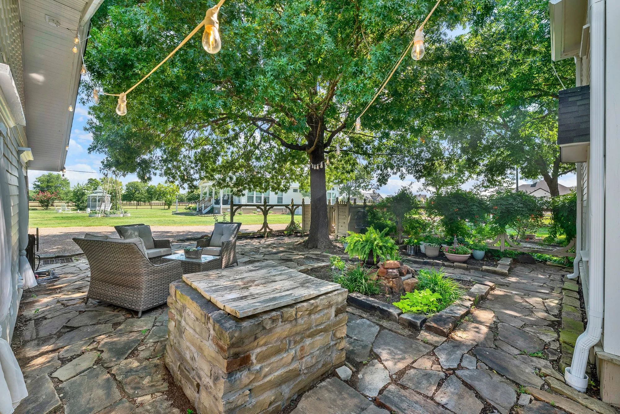 Enjoy the inviting courtyard from another perspective, featuring beautiful stonework and established gardens. The expansive patio offers multiple gathering spaces, blending timeless character with relaxed outdoor living.
