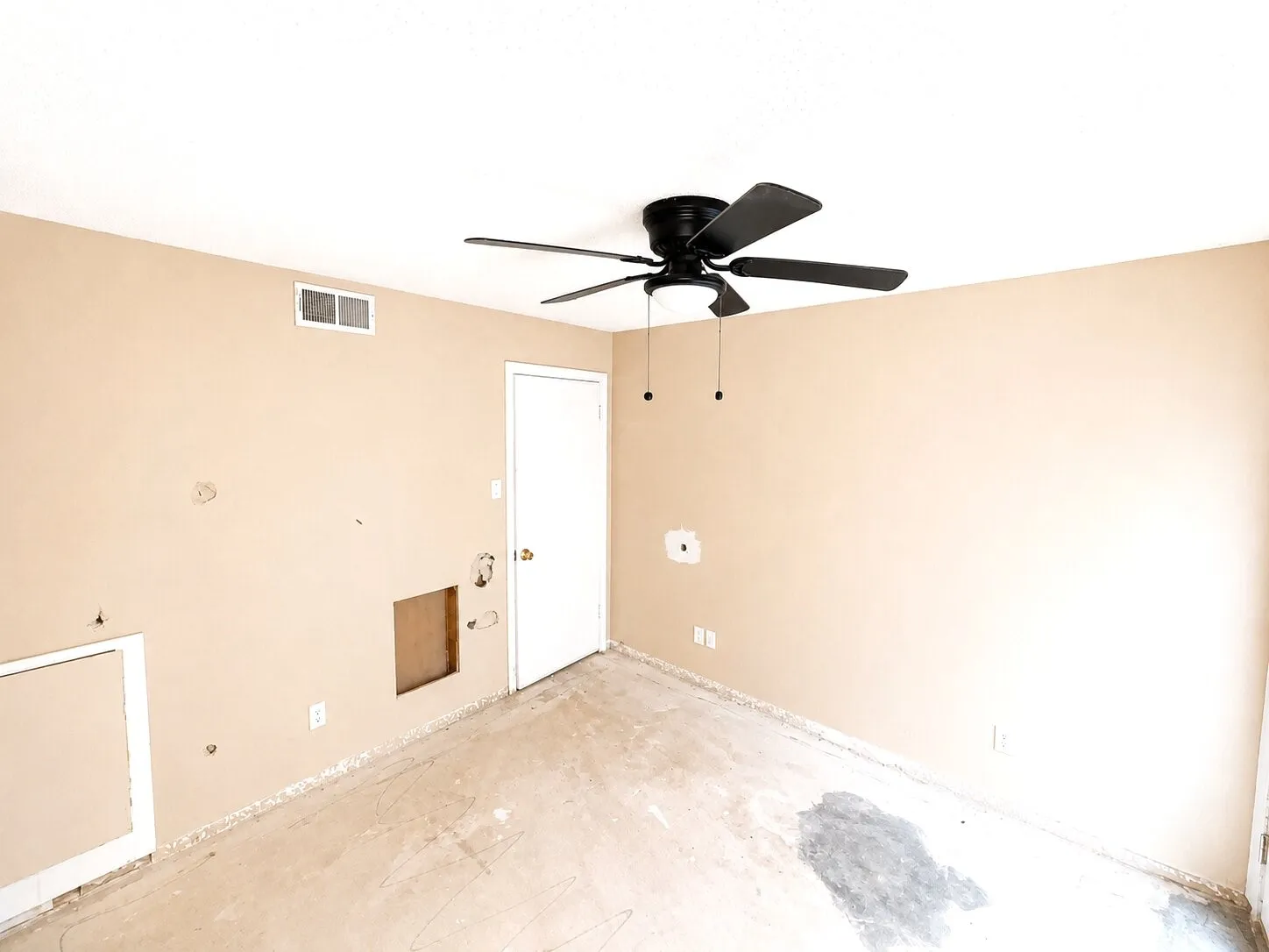 Room with a ceiling fan, white door, and neutral wall paint