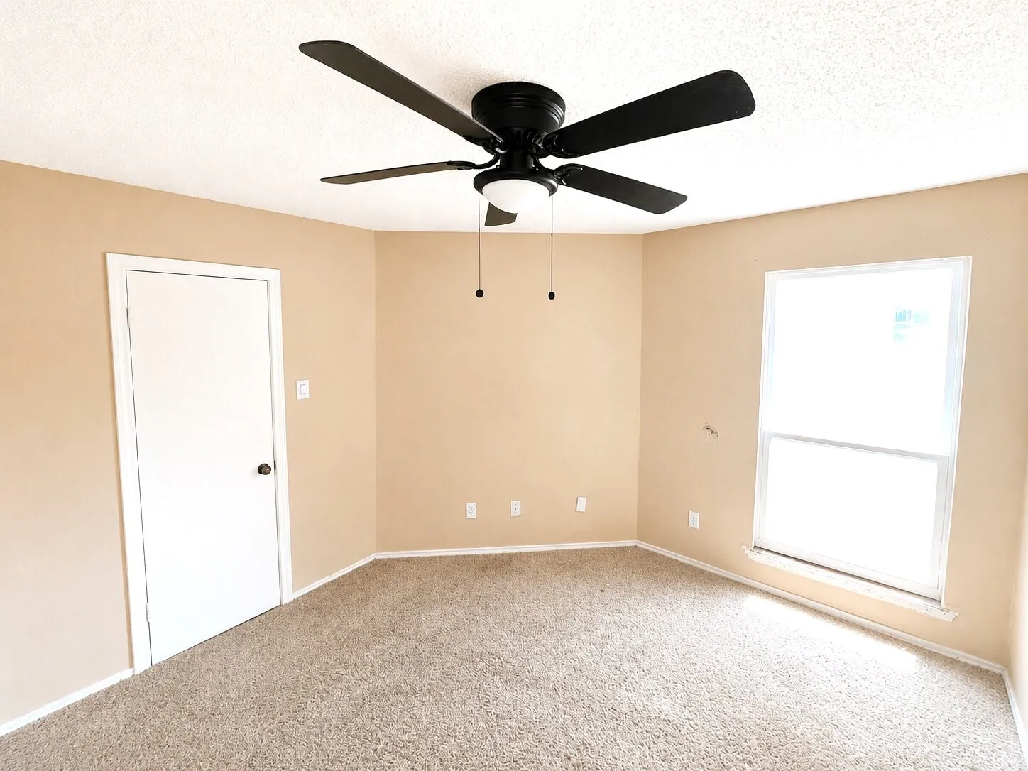 Carpeted room featuring a ceiling fan with integrated lighting, a white panel door, and a white-framed window