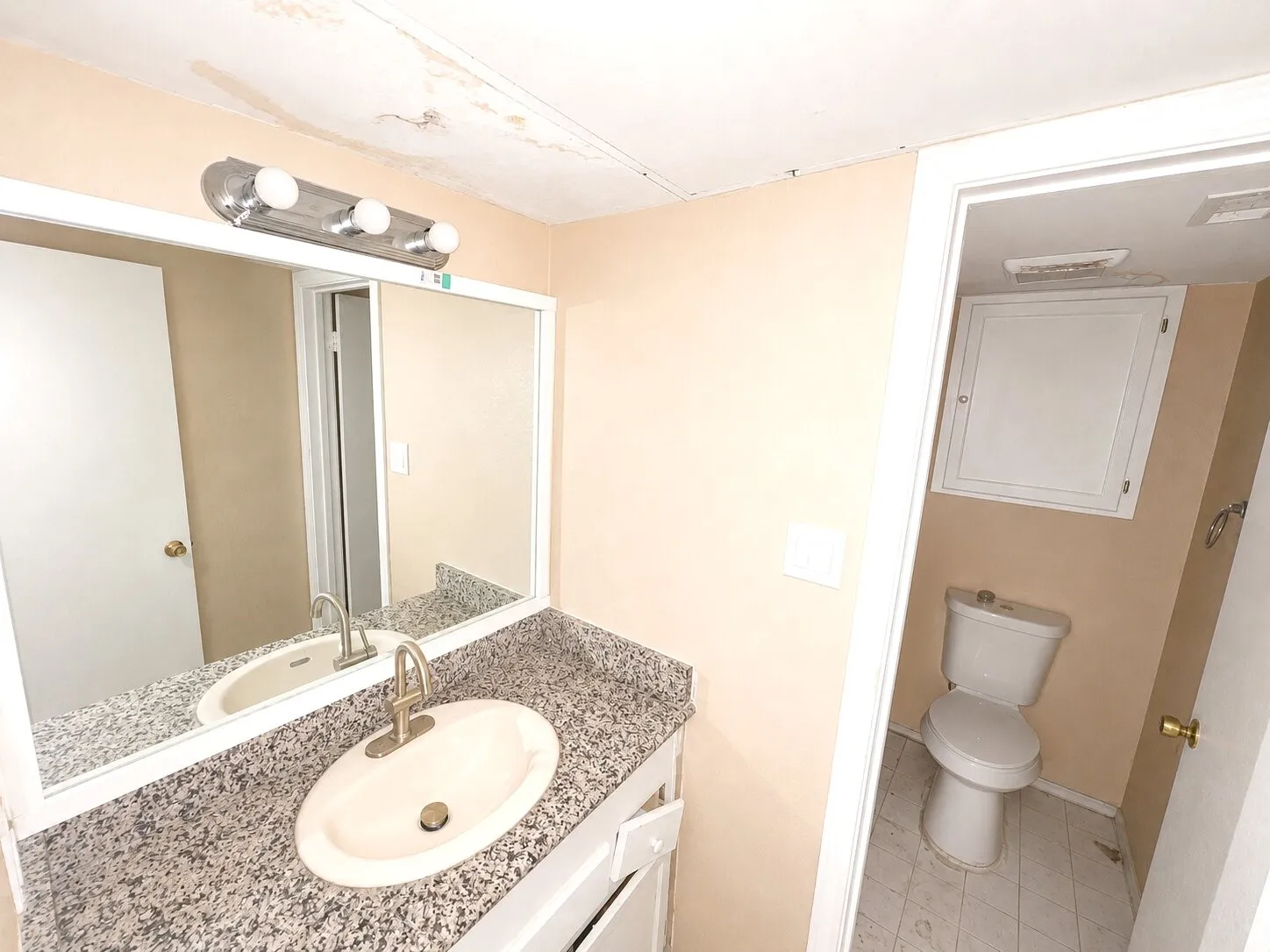 Bathroom vanity featuring a speckled countertop, an undermount sink with a brushed nickel faucet, and a large wall-mounted mirror