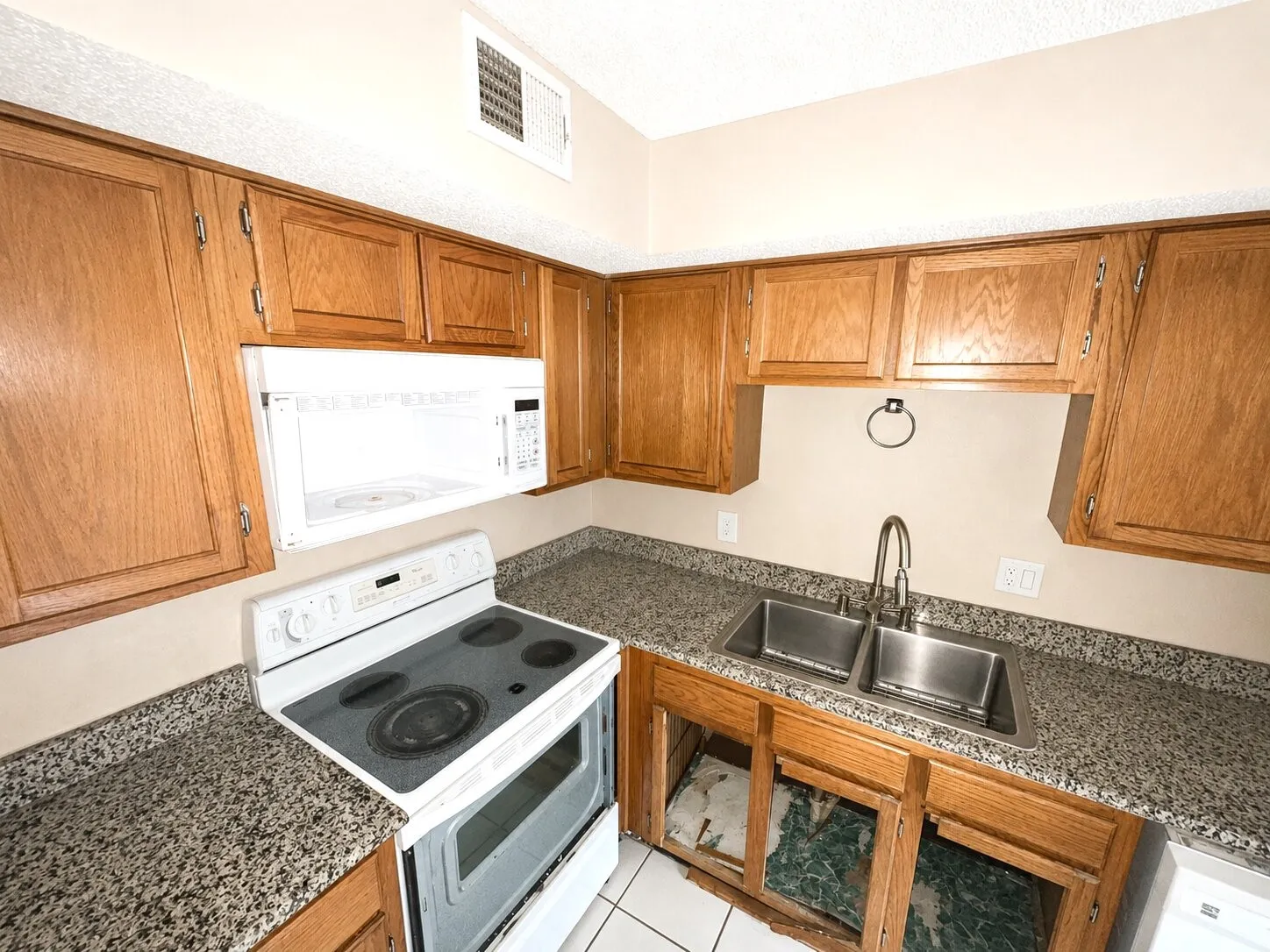Kitchen featuring wood cabinetry, speckled countertops, and a double basin stainless steel sink with a gooseneck faucet
