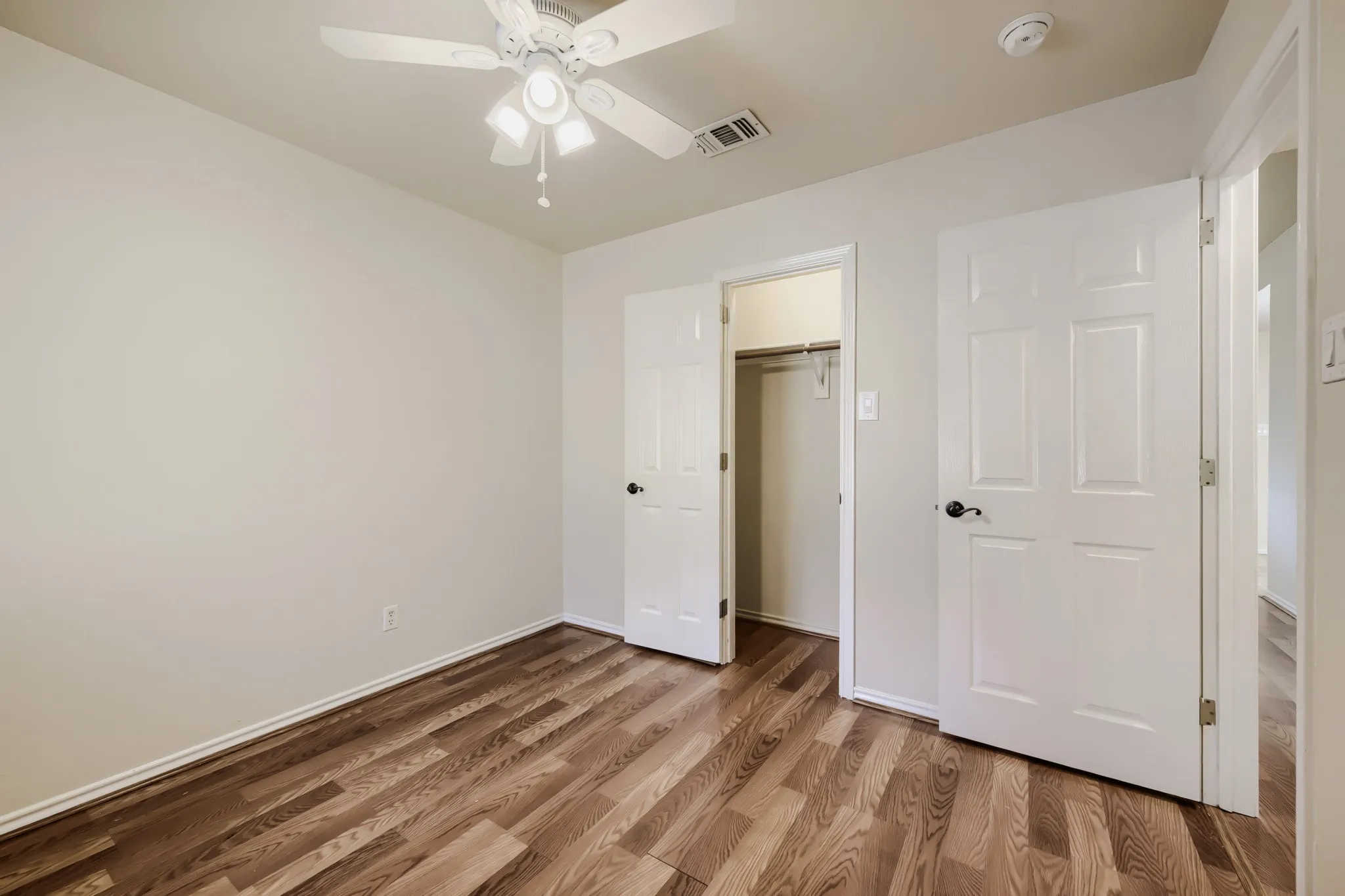 Bedroom featuring wood-finish flooring, a ceiling fan with integrated lighting, and a closet with bifold doors