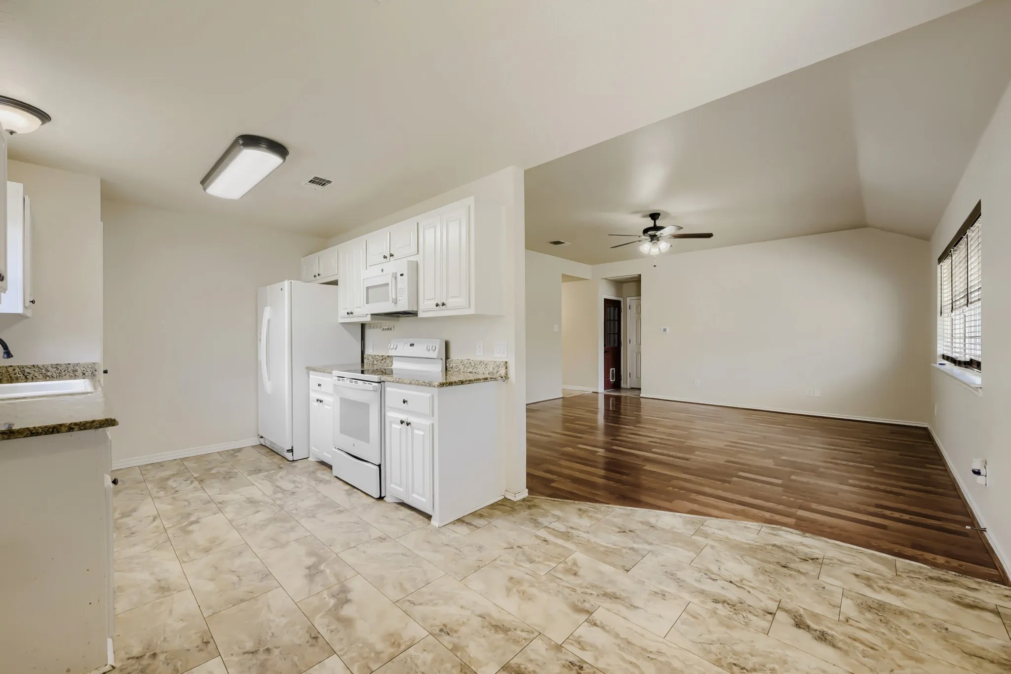 Kitchen area with white cabinetry, granite-finish countertops, and tile flooring