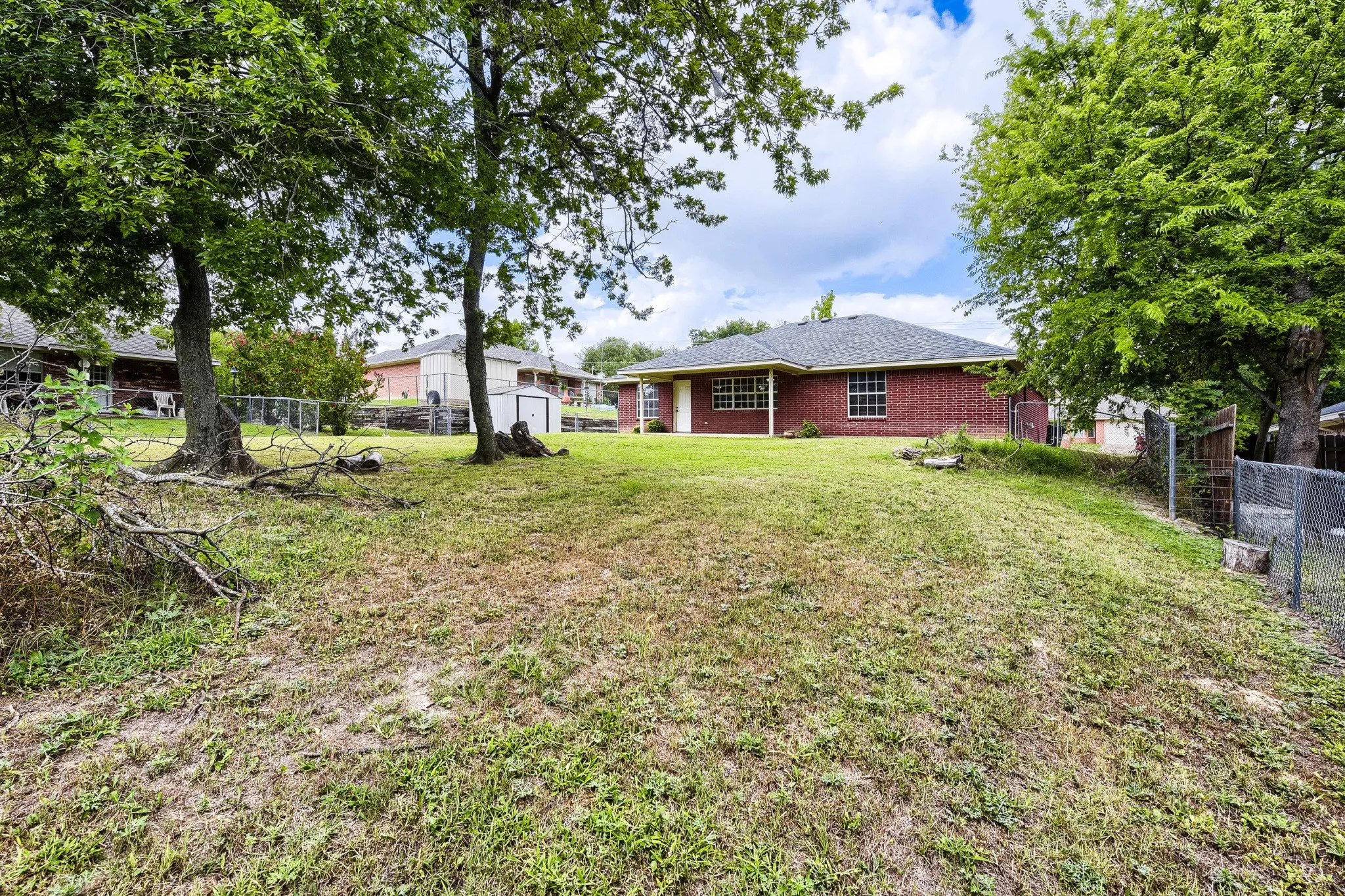 Expansive backyard with a sloped lawn and mature trees