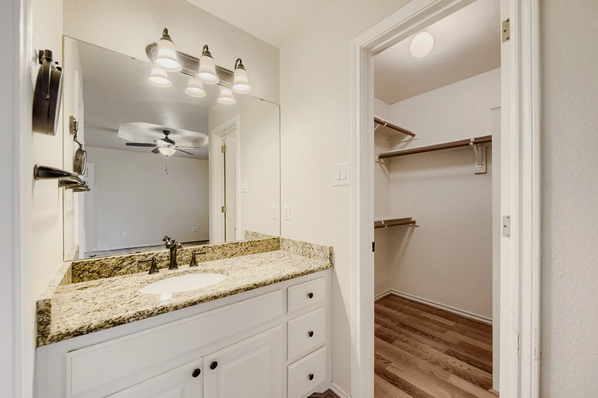 Bathroom vanity with a granite countertop, undermount sink, and dark bronze faucet