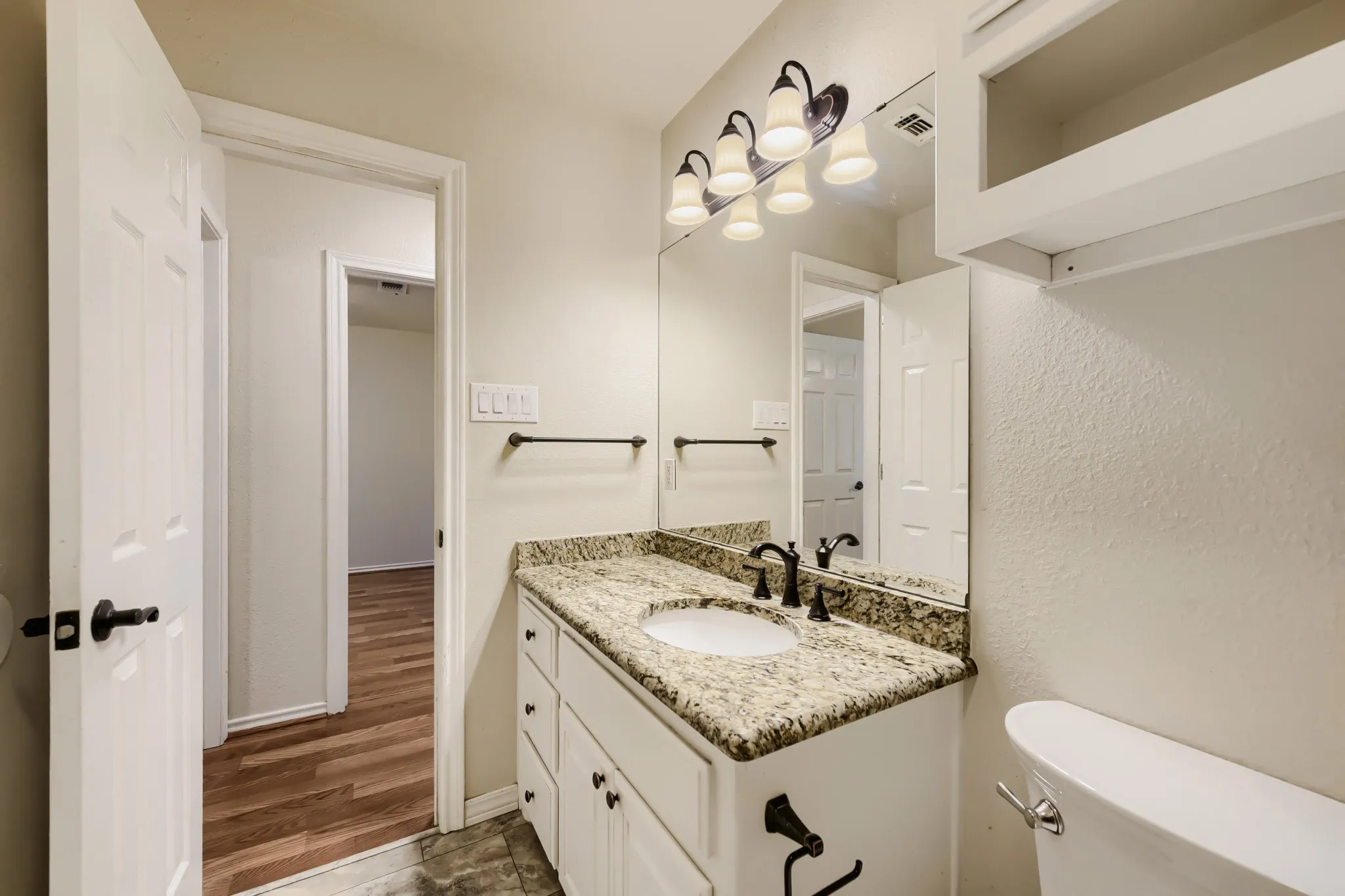 Bathroom vanity with a granite countertop, undermount sink, and matte black faucet