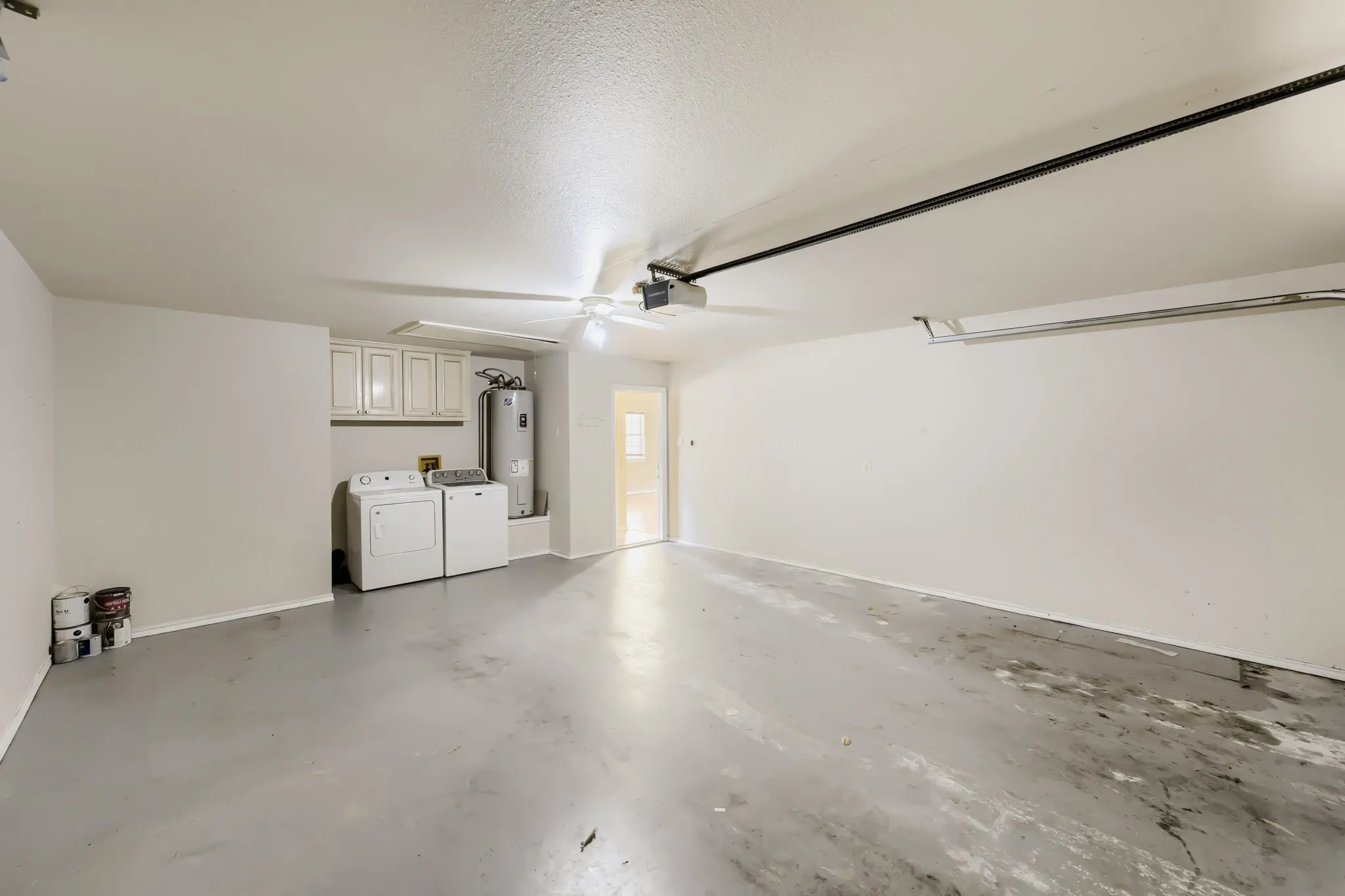Expansive garage space with a light gray painted concrete floor, white walls, and a ceiling-mounted light fixture