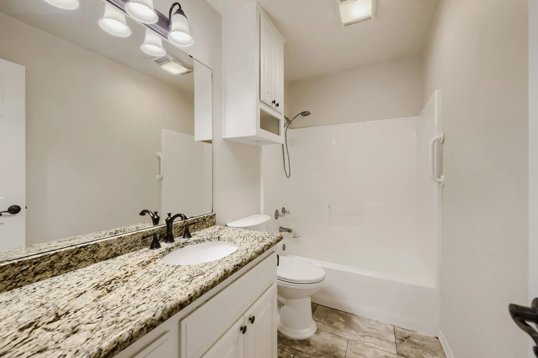 Bathroom featuring a spacious vanity with a granite countertop, undermount sink, and oil-rubbed bronze faucet