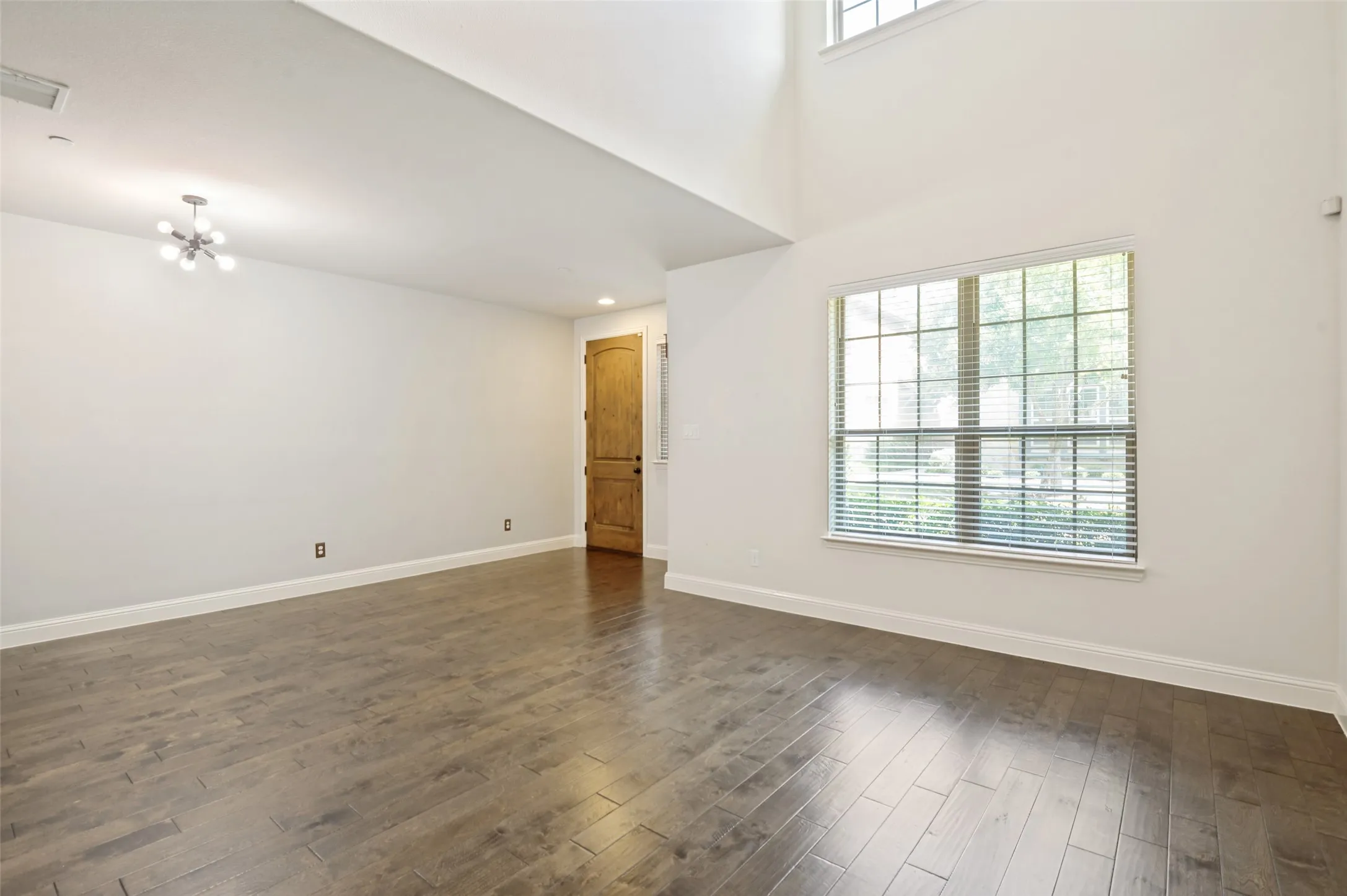 Spacious interior featuring wood-finish flooring, window with blinds