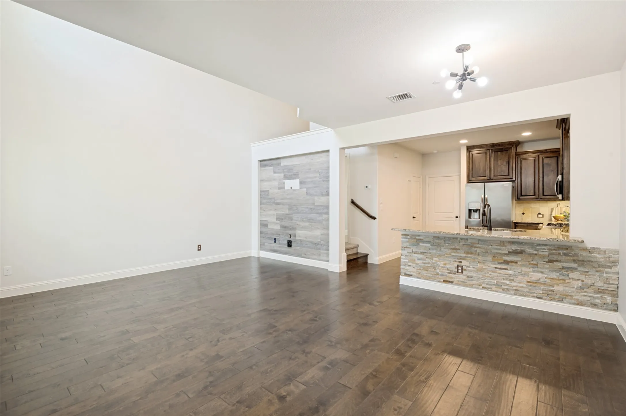 Expansive open-concept living area featuring wood-finish flooring and a vaulted ceiling