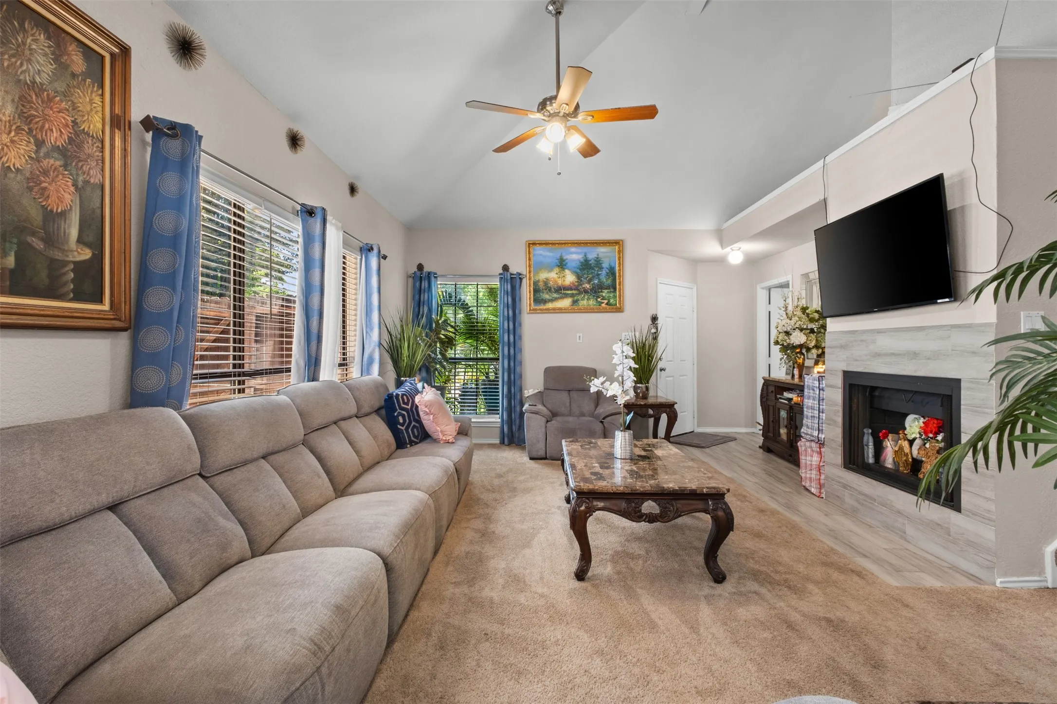 Spacious living area featuring a vaulted ceiling and a ceiling fan