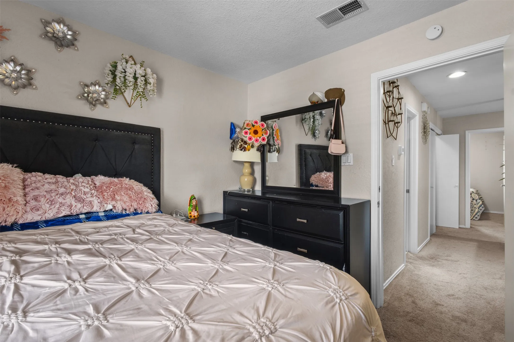 Bedroom featuring a tufted headboard, light-toned wall paint, and carpeted flooring