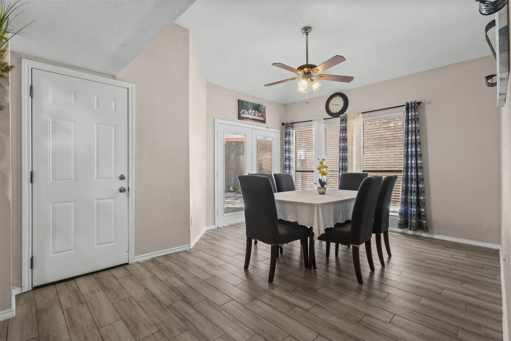 Spacious dining area featuring wood-finish plank flooring and a ceiling fan with integrated lighting