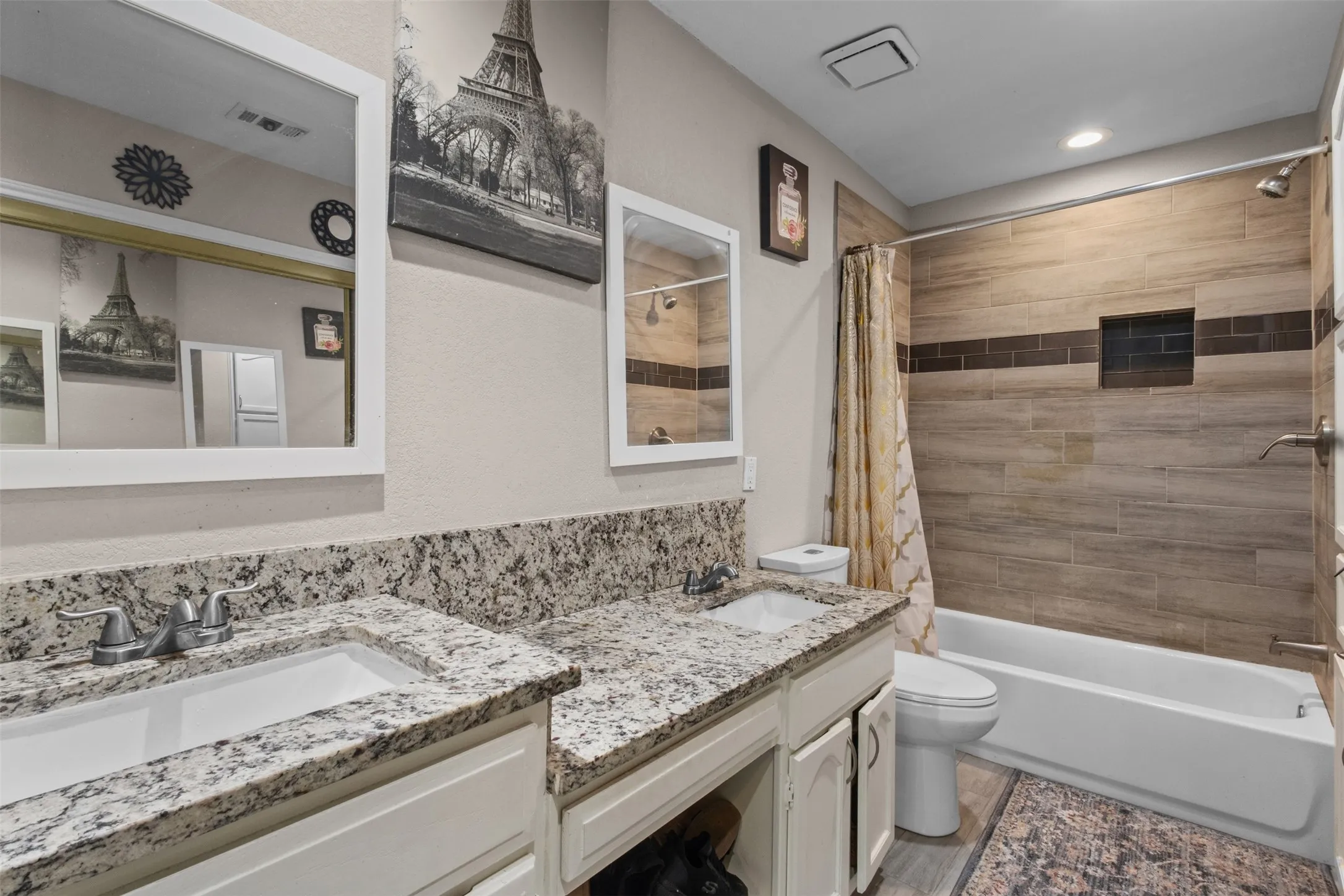 Dual vanity with granite countertops, white cabinetry, and undermount sinks