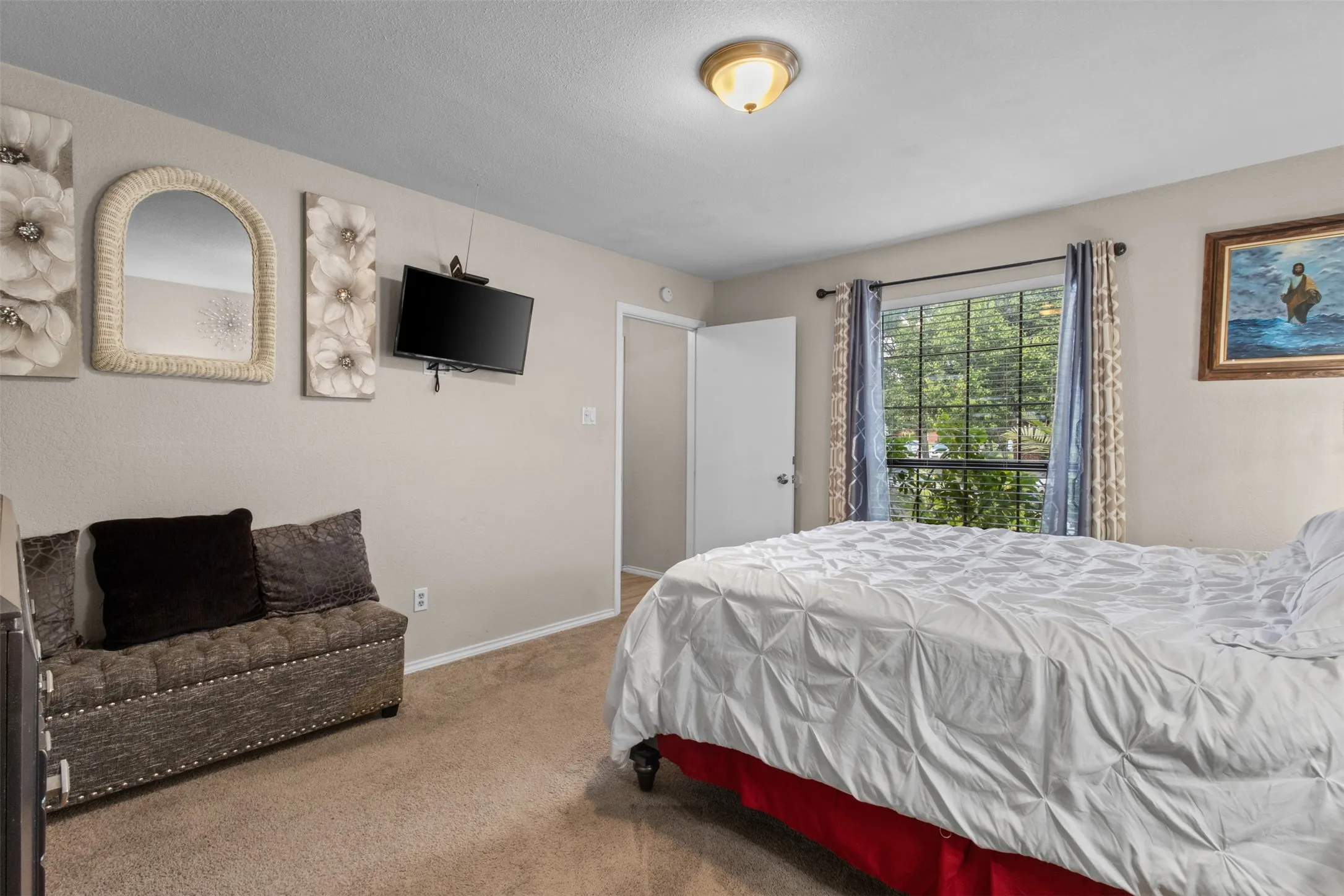 Carpeted bedroom with a large window, a ceiling-mounted light fixture, and a white interior door